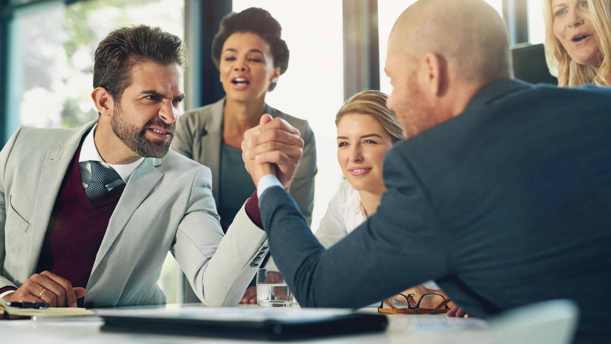 Serious, businessmen and arm wrestle in office for corporate challenge and strength contest. Male employees, team building and meeting in boardroom for corporate competition, conflict or disagreement