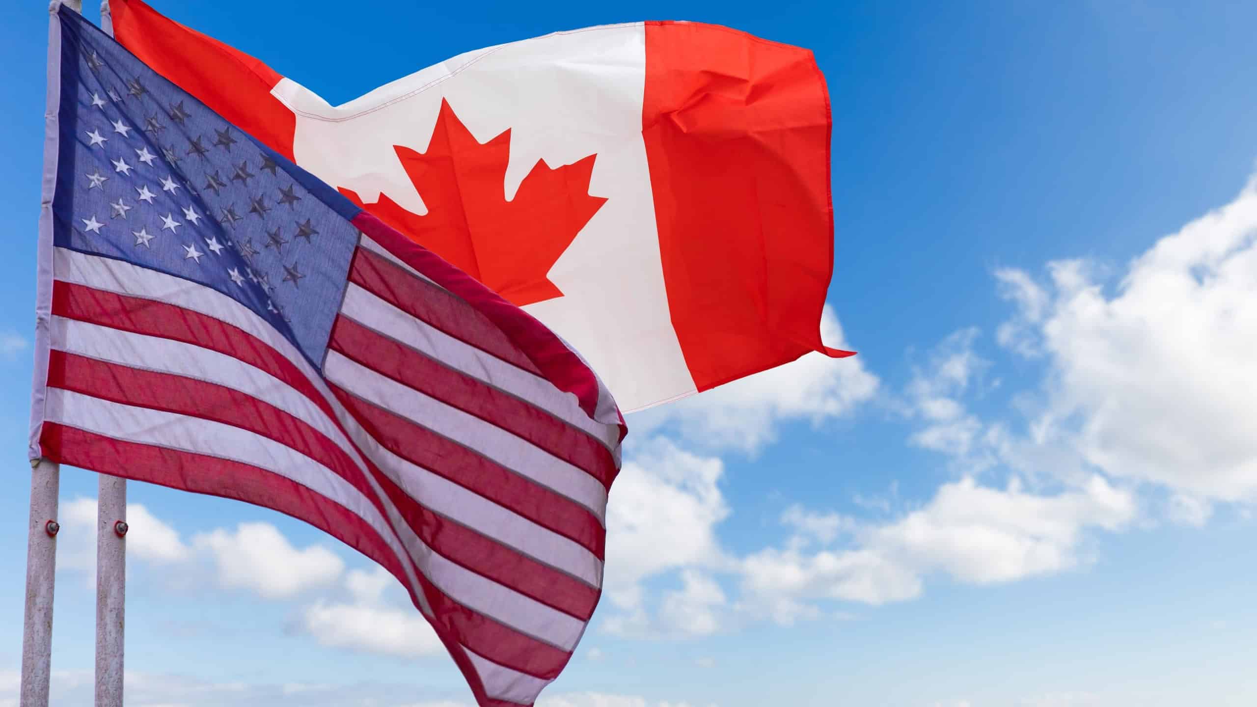 USA and Canada flags against cloudy sky. waving in the sky