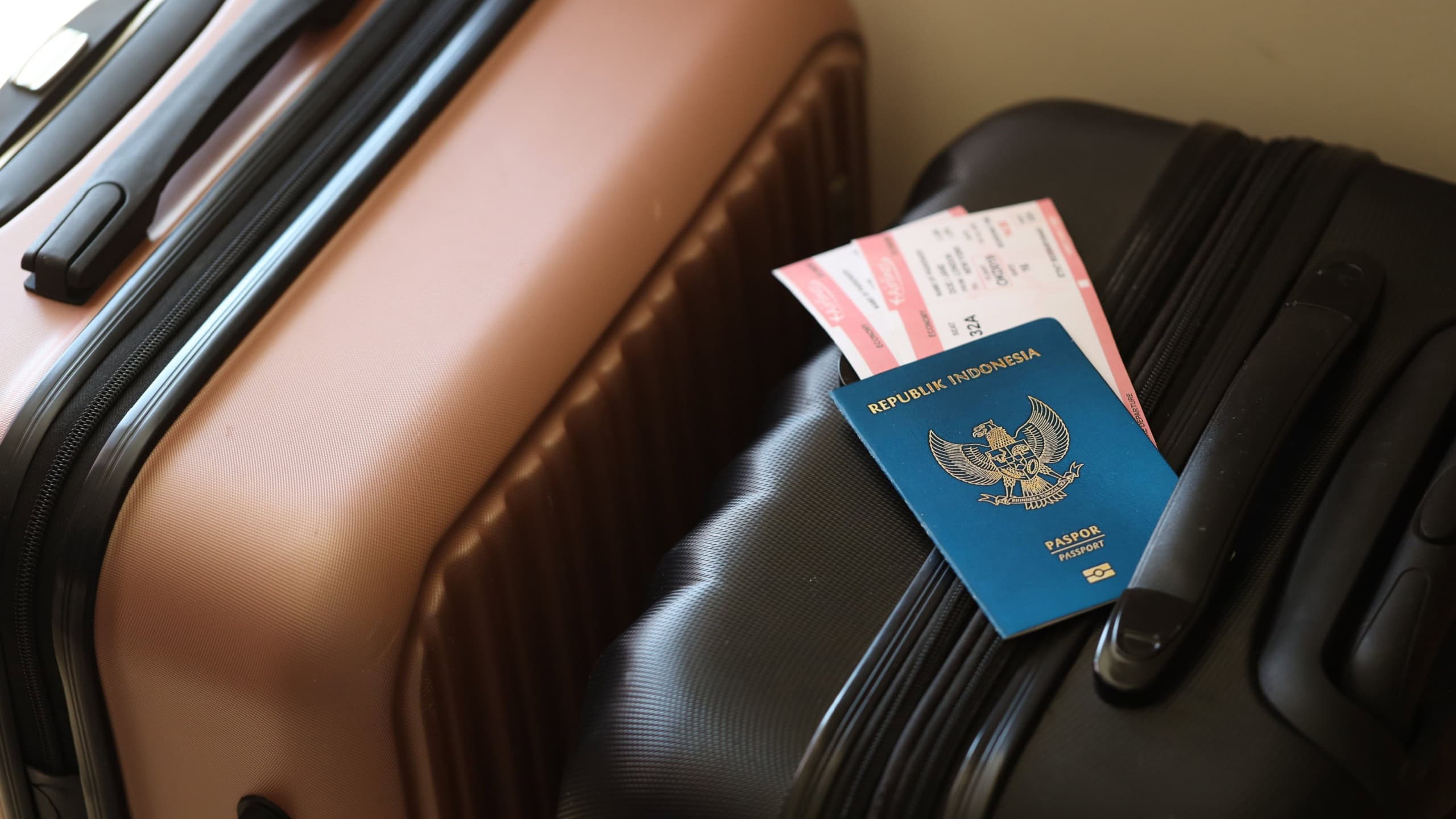 Indonesian passport with tickets lies on touristic suitcase close up in airport waiting hall