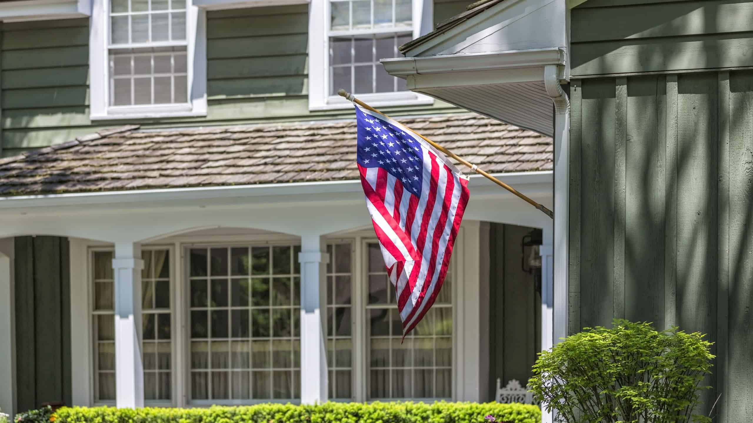 American flag wawing in front of typical american house.