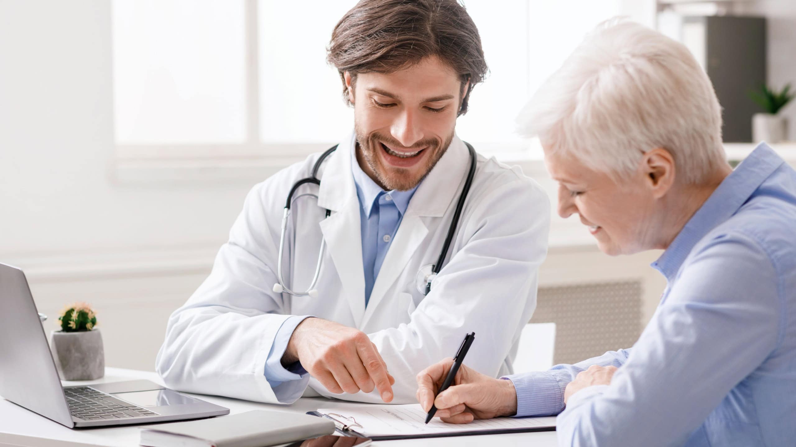 Treatment assignment. Cheerful senior woman signing contract with doctor at hospital, free space