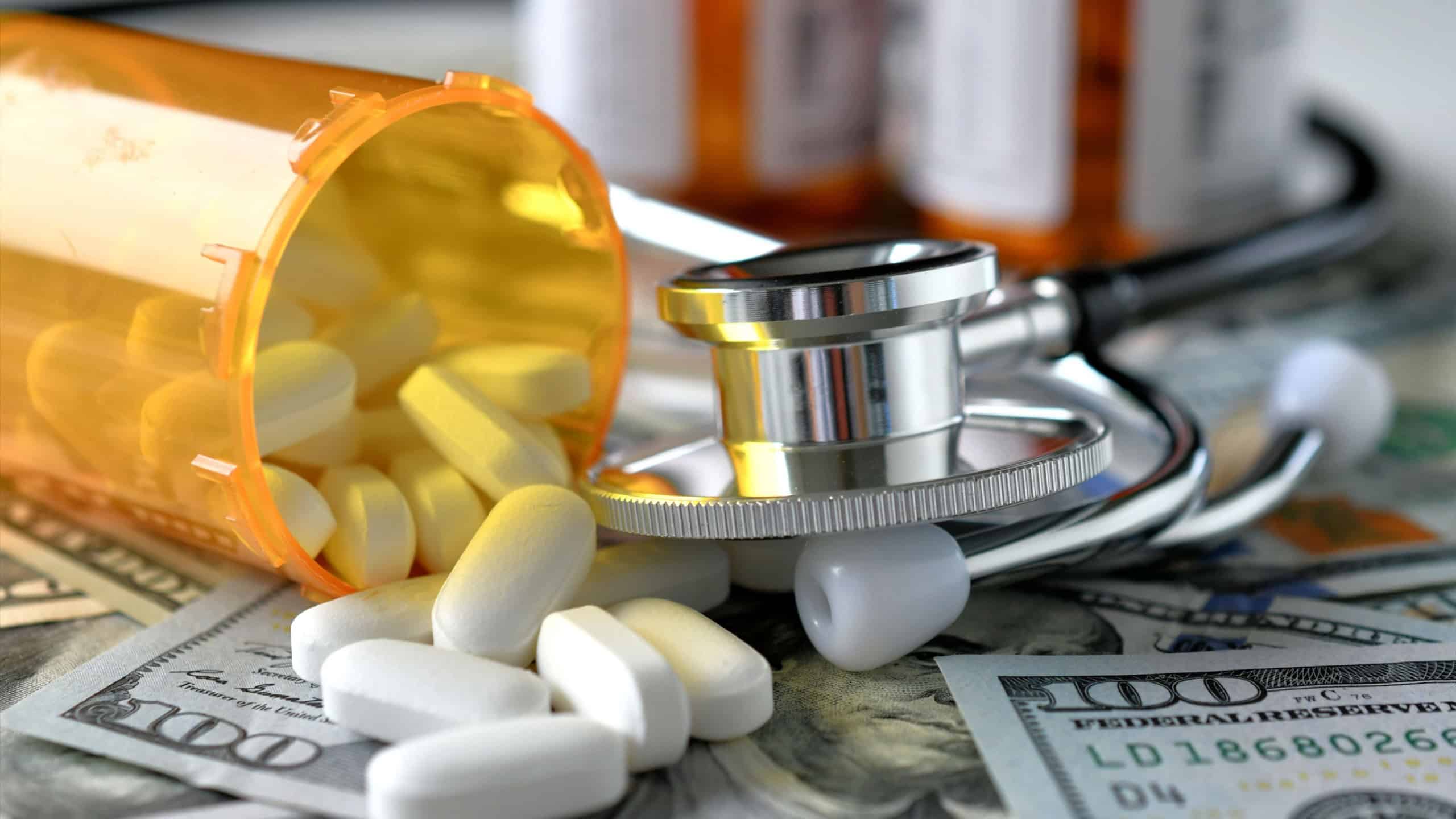 Stethoscope laying on medicine white pills money with RX prescription drug bottle HSA FSA costs