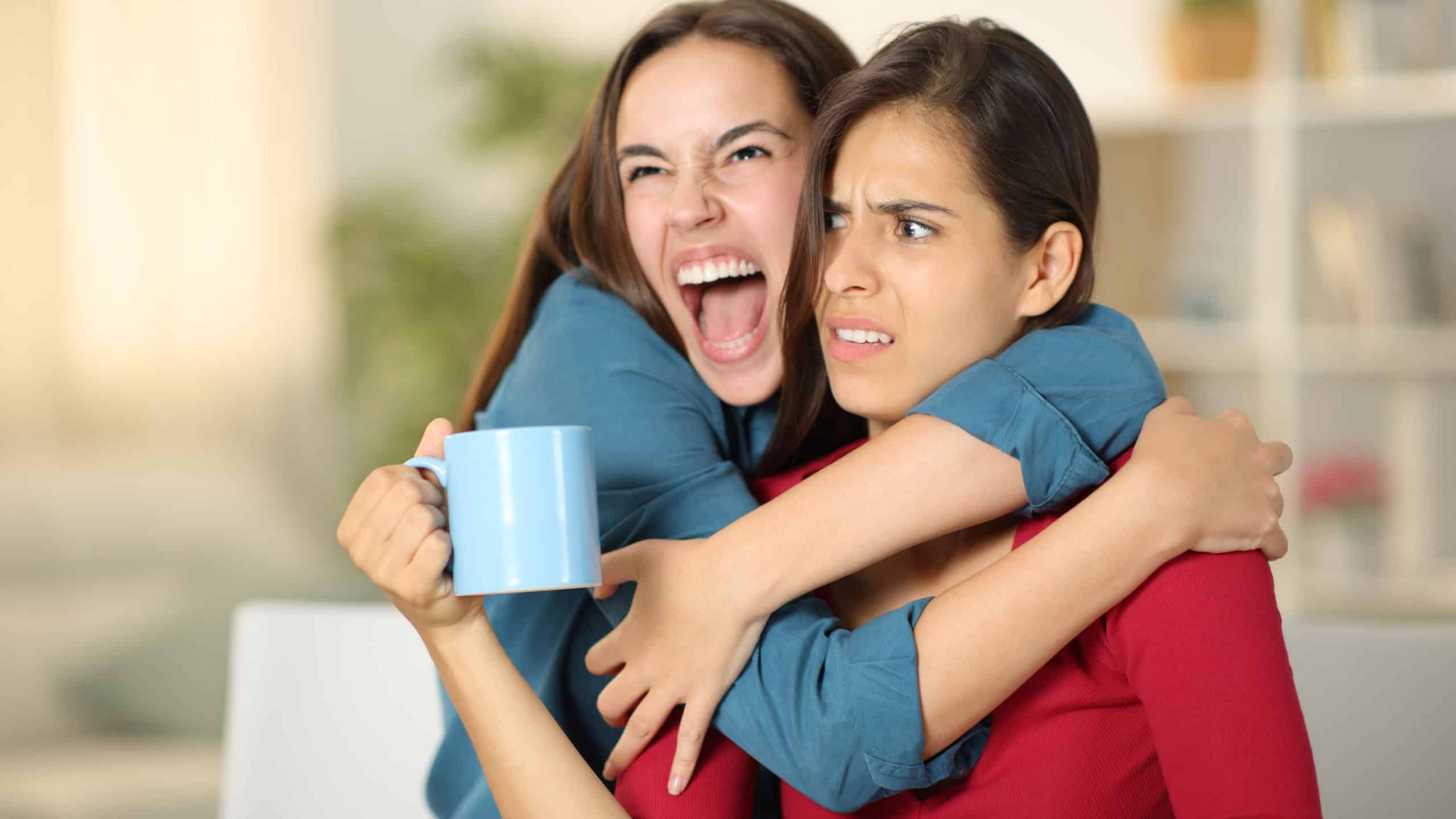 Excited woman hugging to an upset friend at home