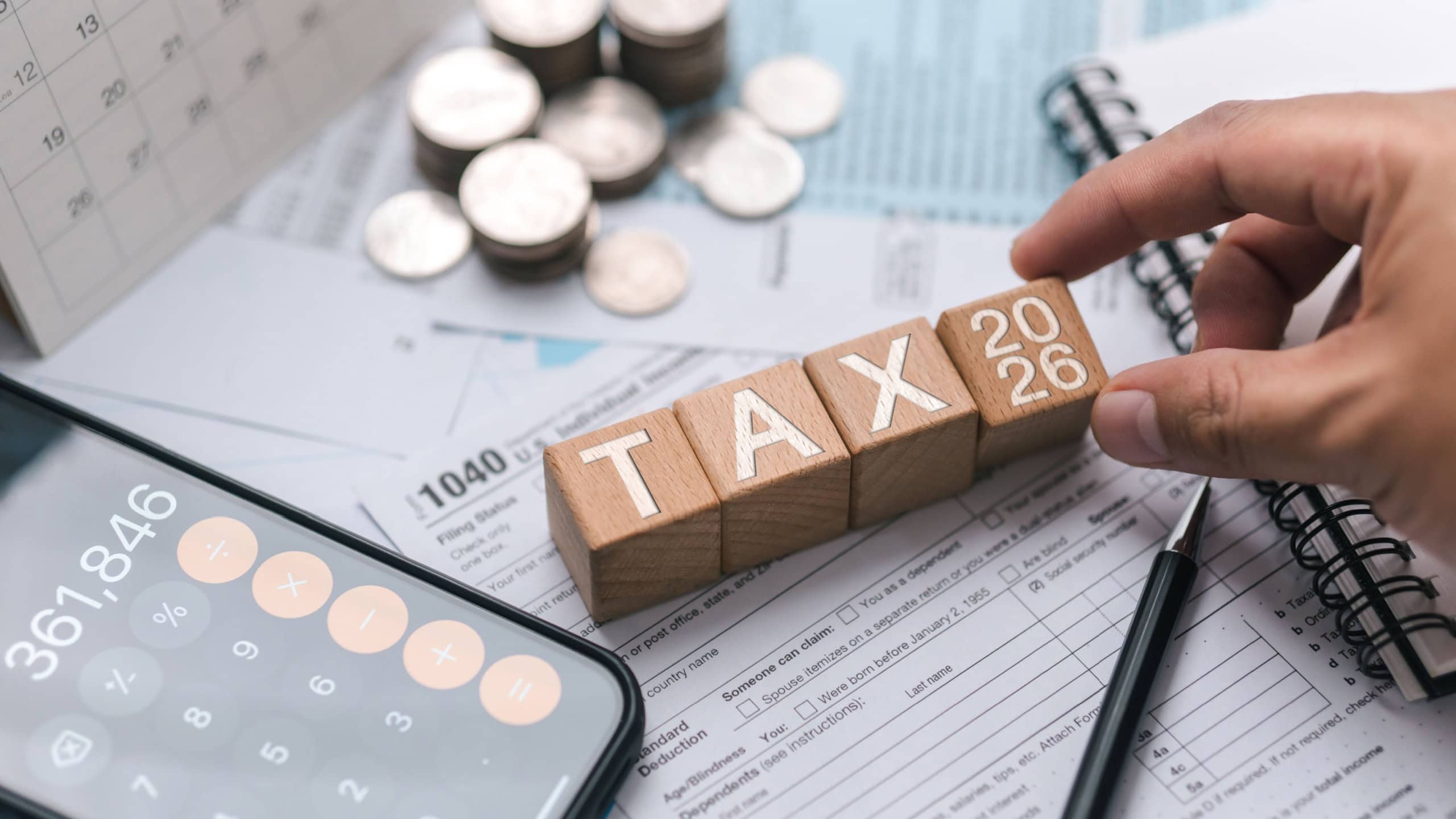 Tax planning concept for 2026. Wooden blocks with the word tax. Calculator on phone. Interest, Financial calculations, Tax law, Tax payment, Government taxes and budget planning.