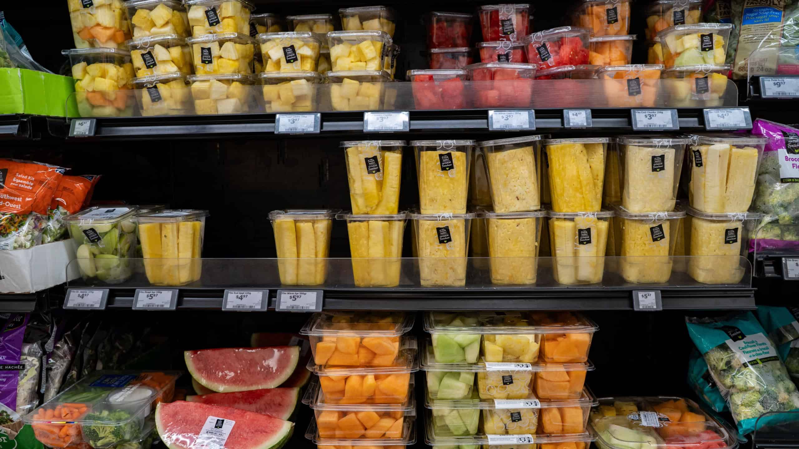 Precut pineapple melon and watermelon packs on grocery shelf. Toronto, Canada - October 3, 2025.