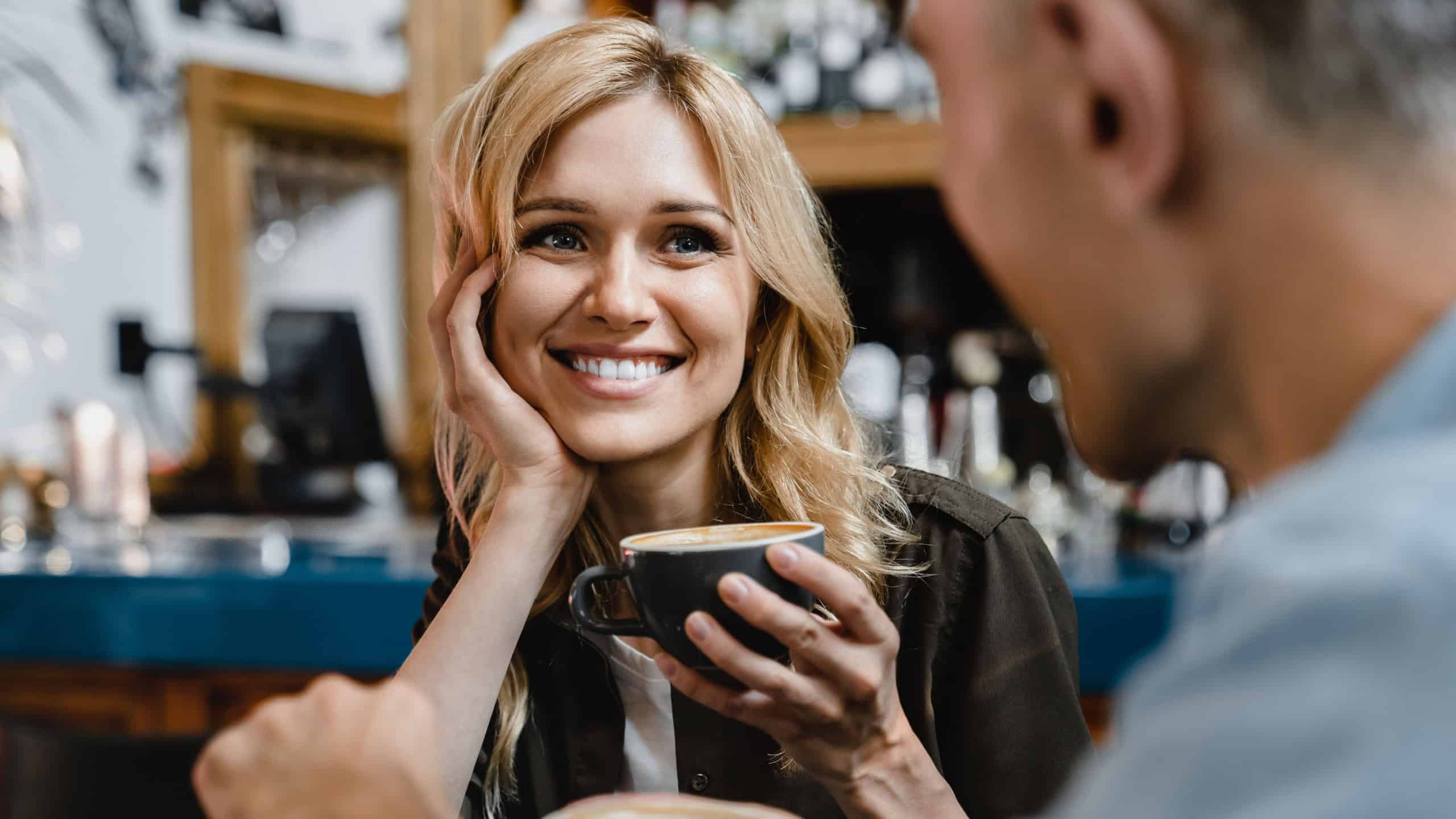 Interested excited falling in love mature woman listening to her husband man boyfriend while drinking coffee in restaurant cafe on a date