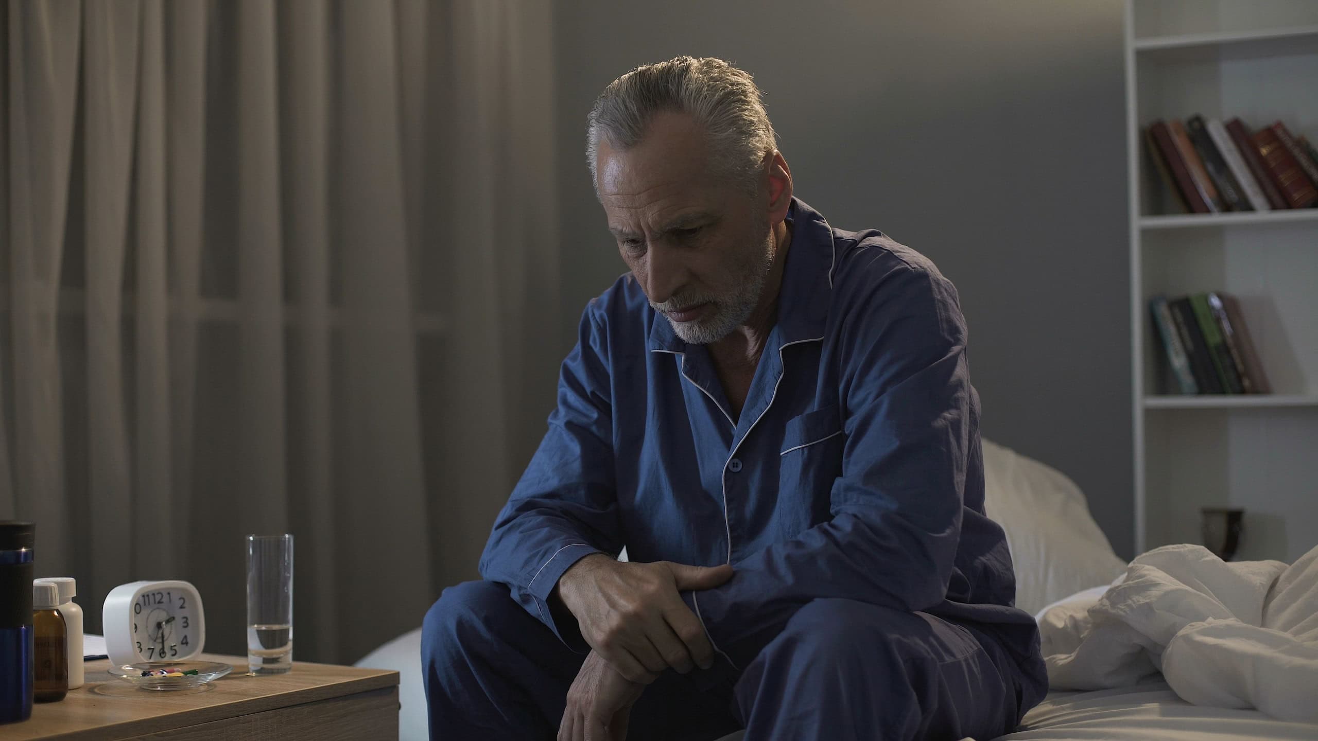Depressed senior person sitting in bed and suffering from insomnia, health
