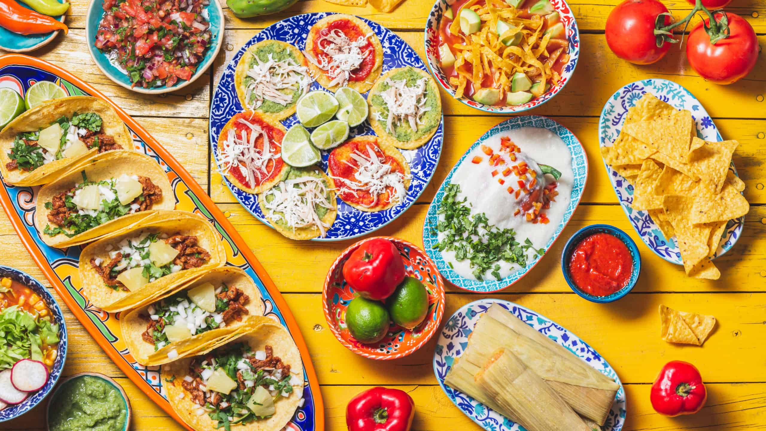 Mexican festive food for independence day - independencia chiles en nogada, tacos al pastor, chalupas pozole, tamales, chicken with mole poblano sauce. Yellow background