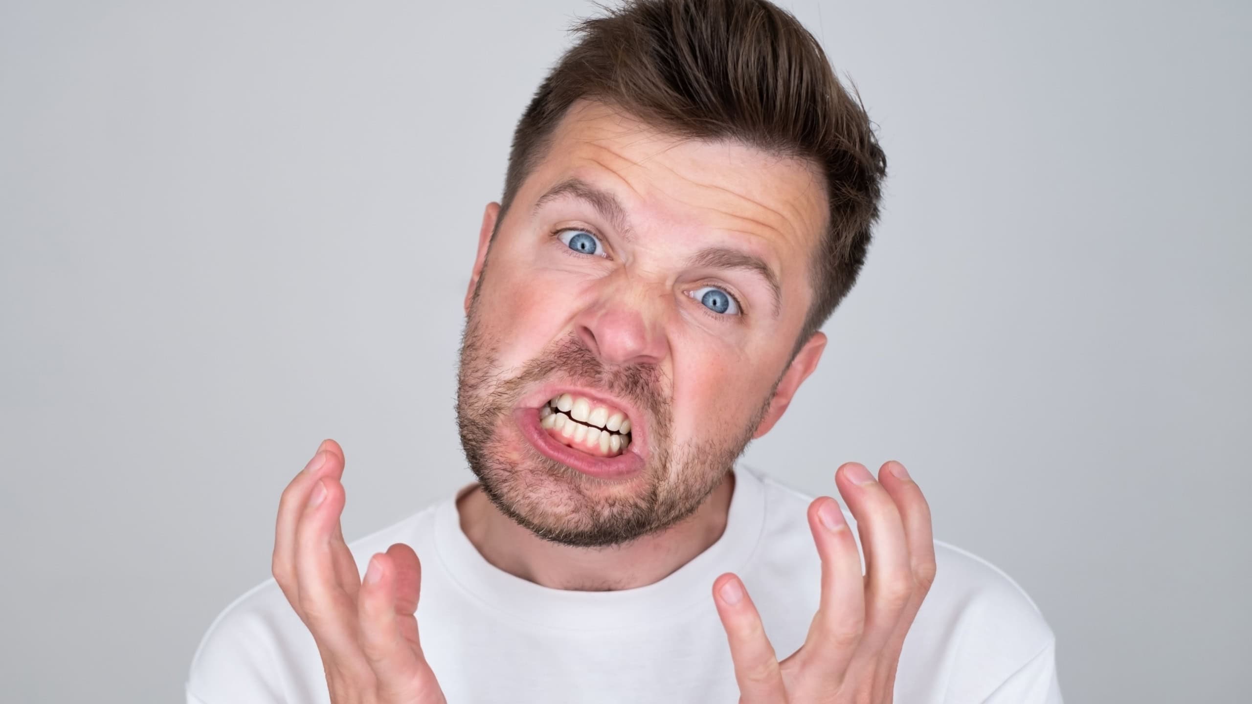 handsome man angry shouts, insulting someone with cruel words.