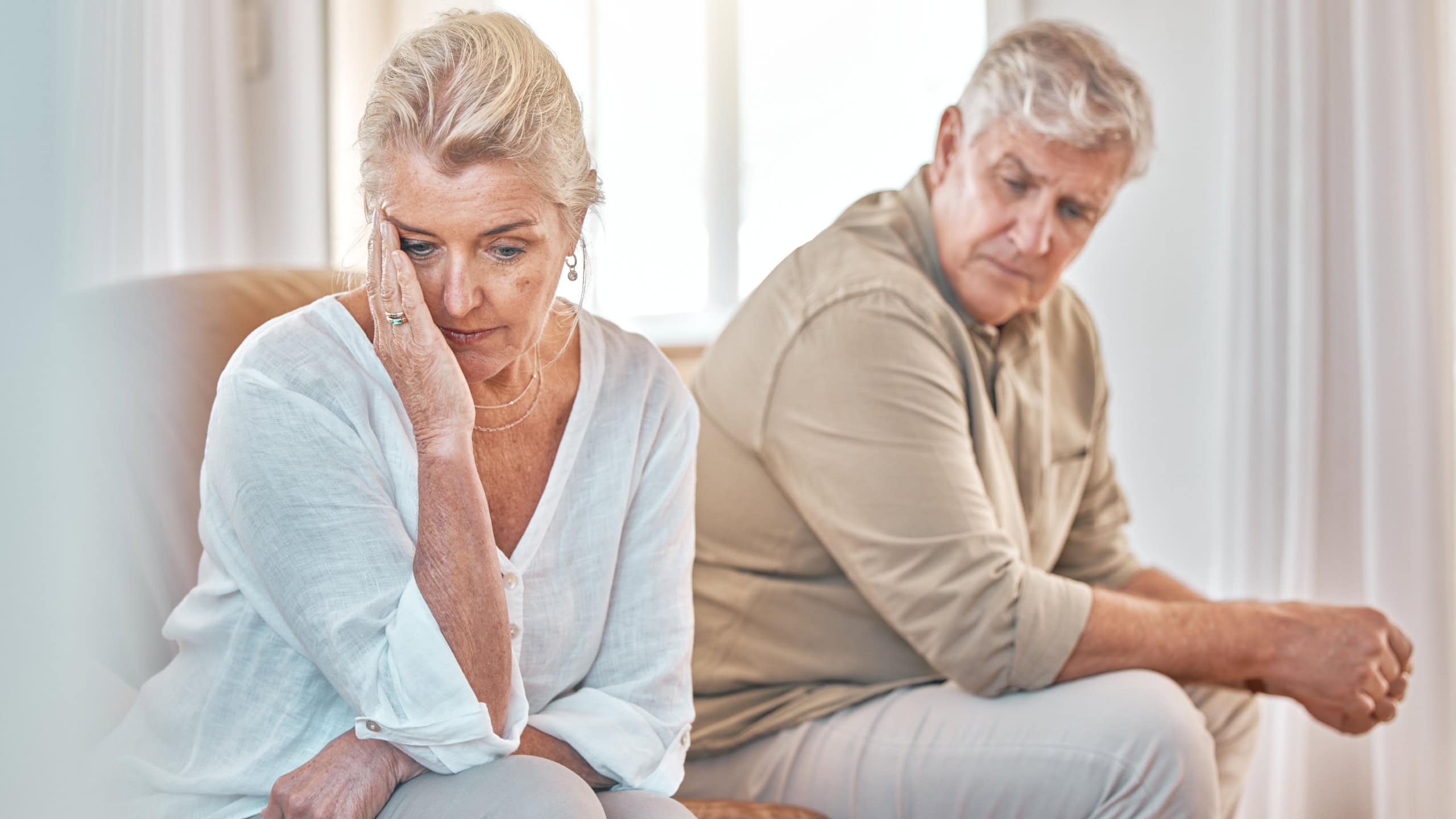 Senior couple, divorce and headache in fight, conflict or argument on the living room sofa at home. Elderly man and frustrated woman in depression, cheating affair or toxic relationship in the house