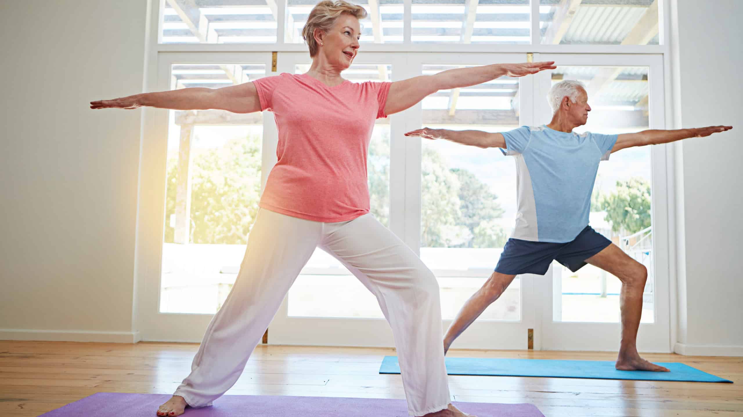 Yoga, stretching and senior couple in home for fitness, health and wellness with warrior pose. Workout, mature man and woman on mat for pilates, balance and body care exercise together in retirement.
