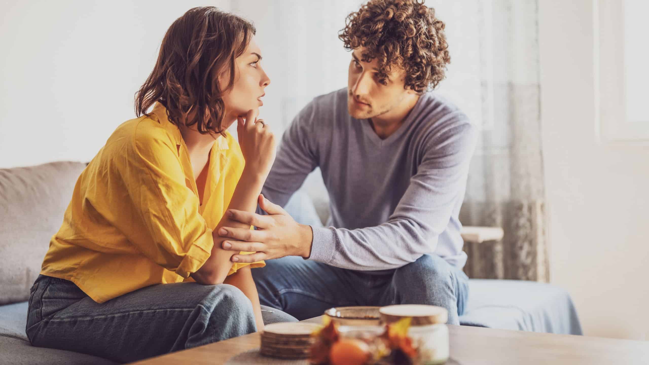 Man and woman are sitting at sofa and arguing. Relationship problems.