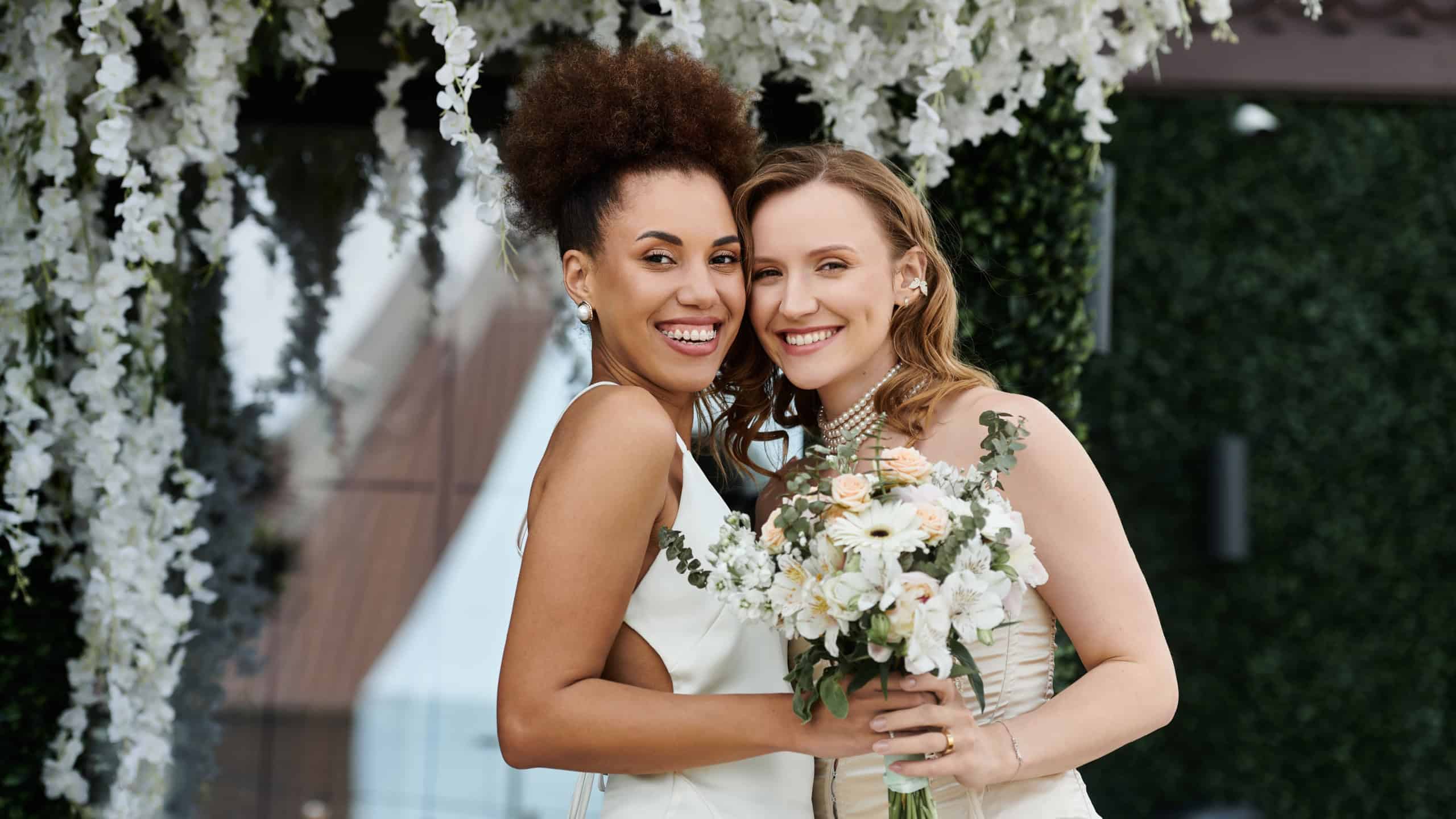 A lesbian couple smiles happily on their wedding day.