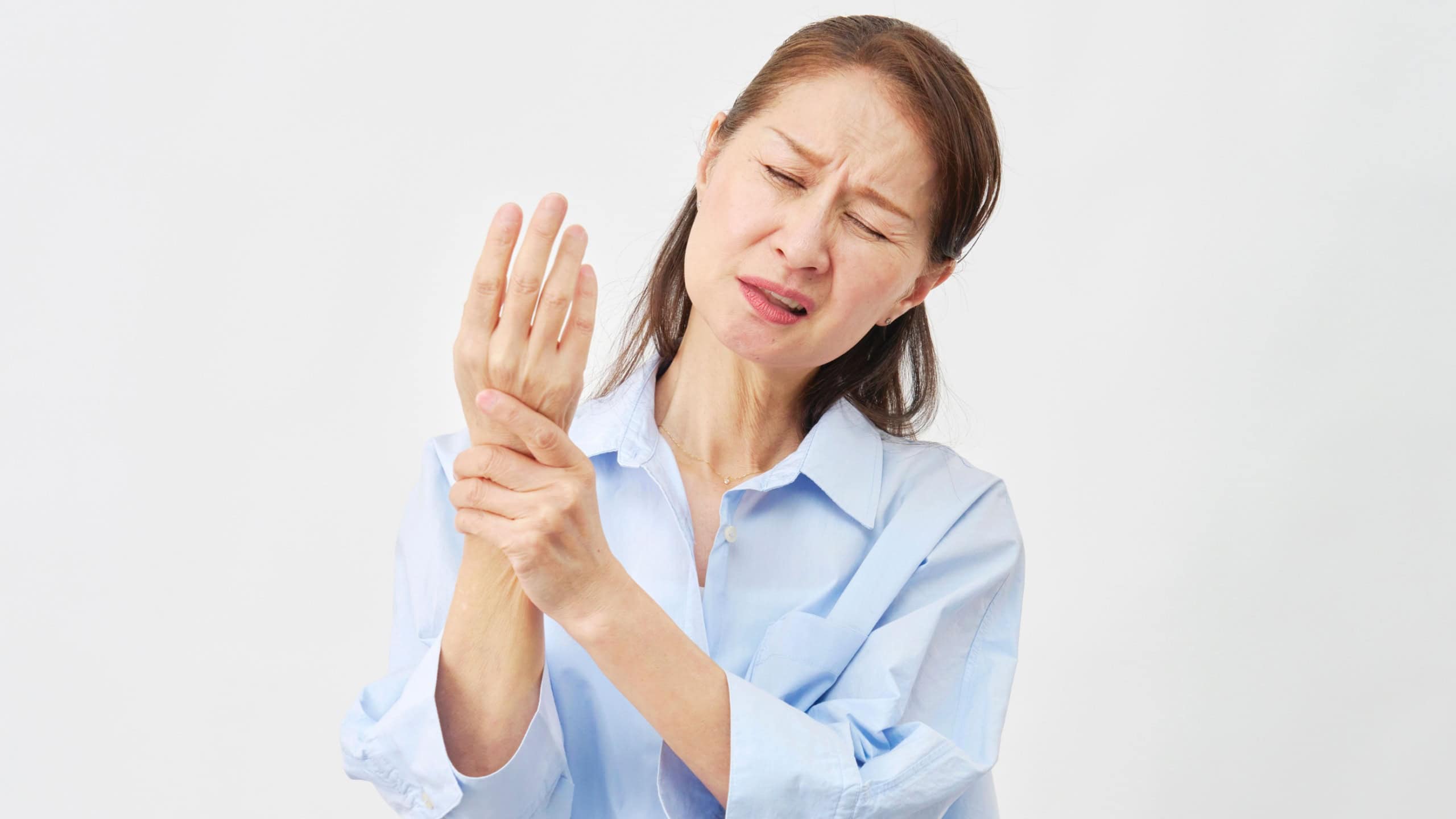 Asian senior woman suffering from wrist pain and holding wrist on white background