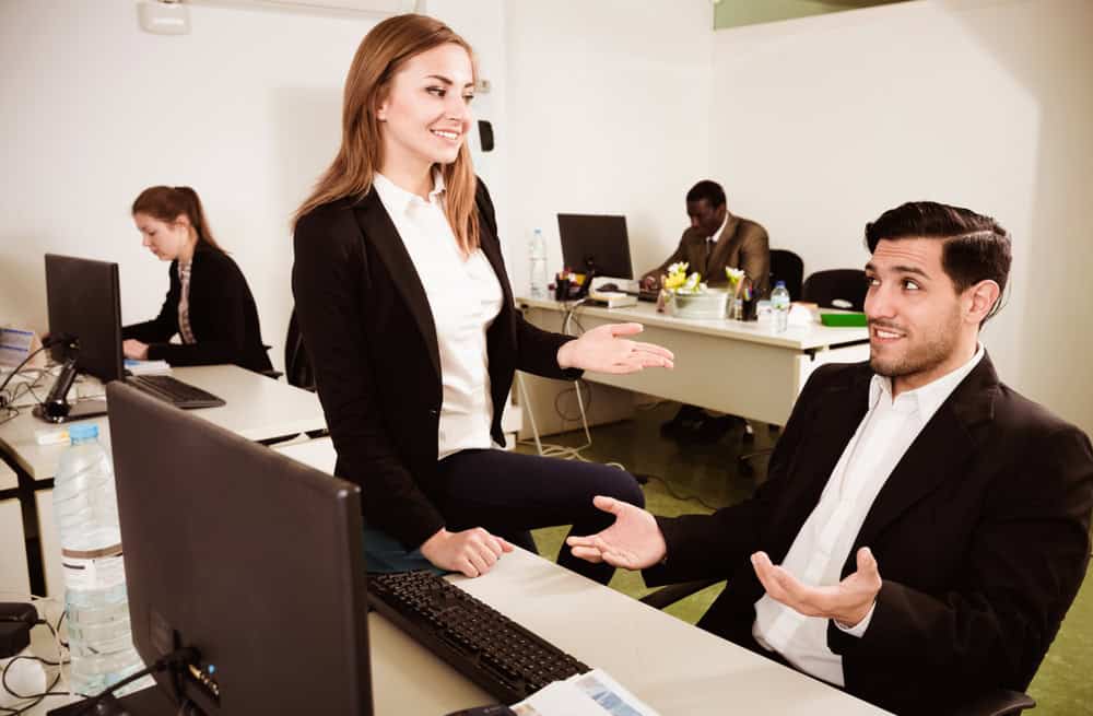 Young positive businesswoman flirting with Hispanic male colleague during work in modern coworking space