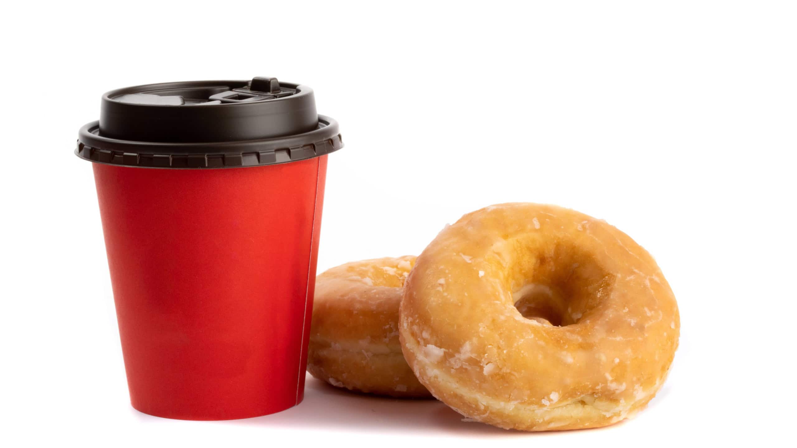 two honey dipped donuts beside a red take away coffee cup isolated on white