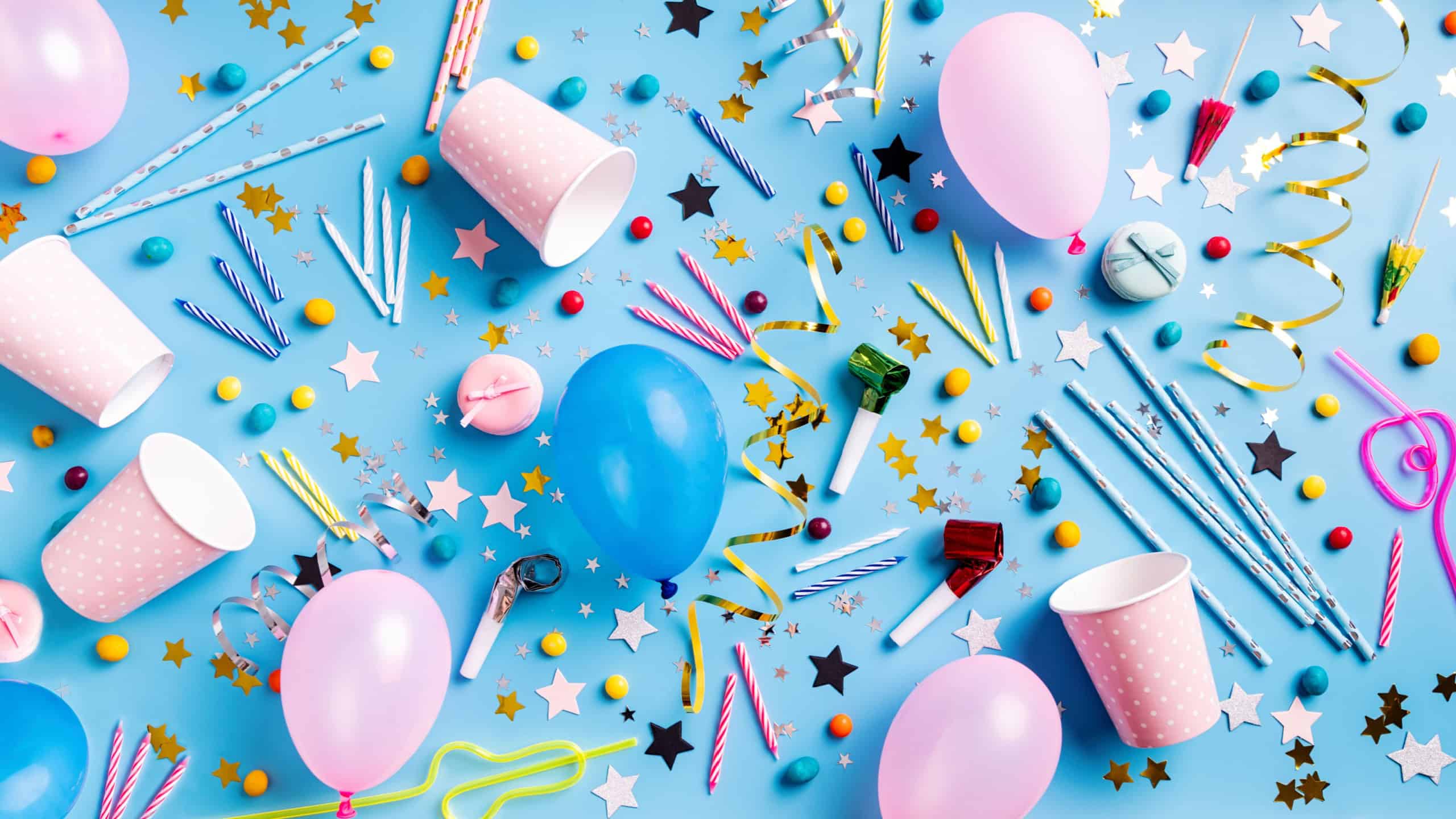 Birthday party background. Balloons, candles, confetti, candies and party supplies on blue, top view flat lay banner