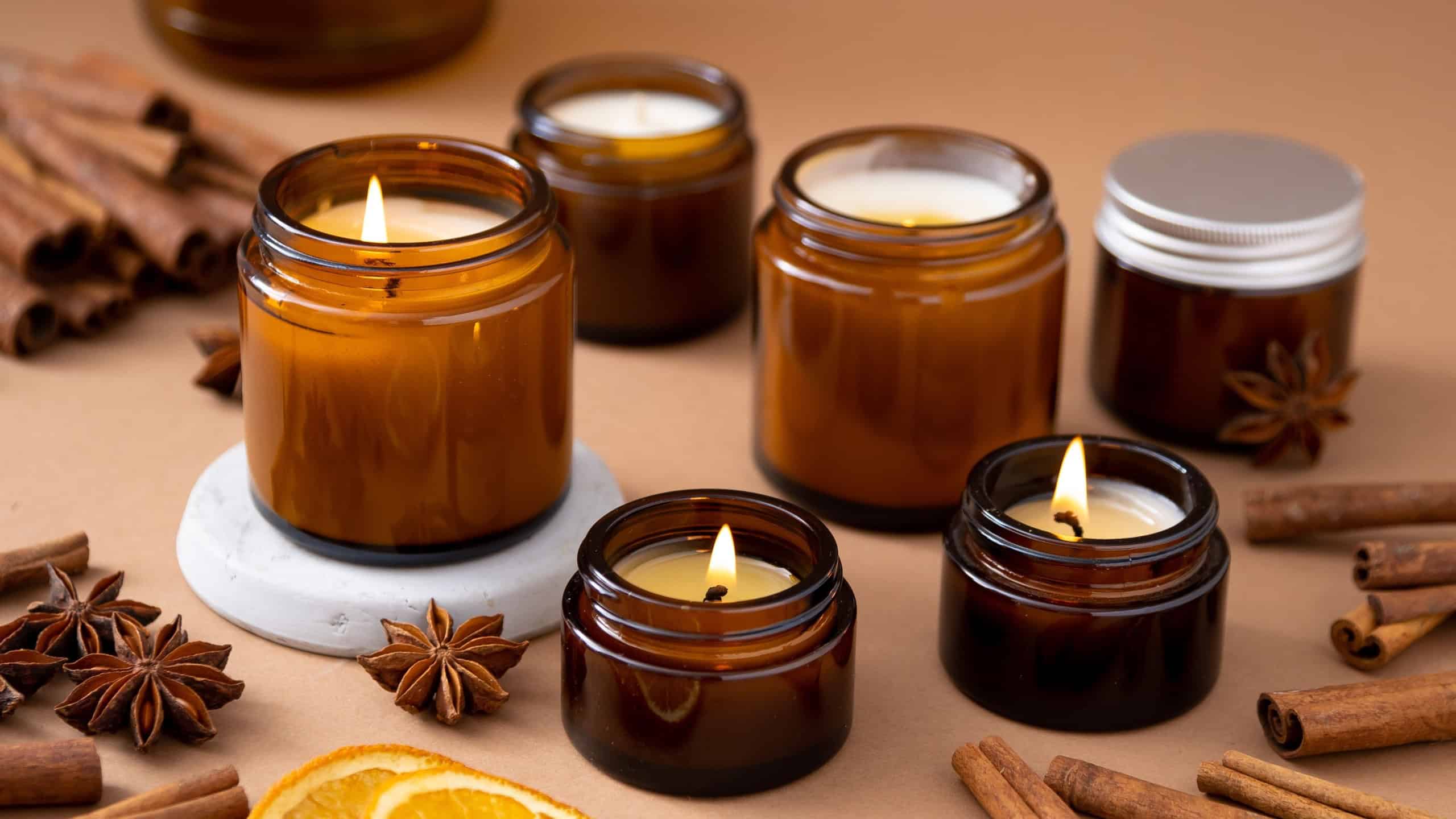 A set of different aroma candles in brown glass jars. Scented handmade candle. Soy candles are burning in a jar. Aromatherapy and relax in spa and home.