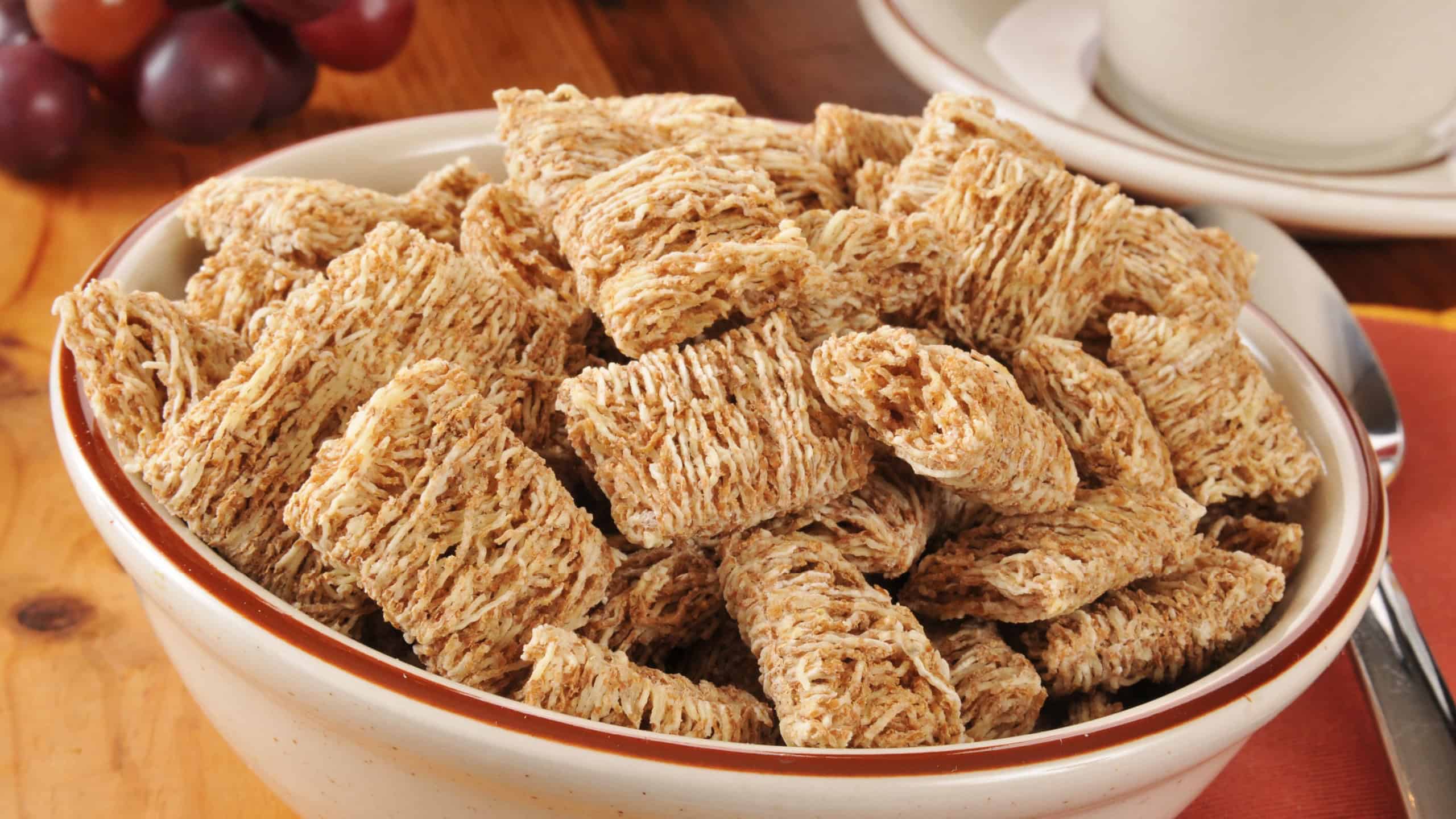 A bowl of shredded organic wheat biscuits with a cup of coffee