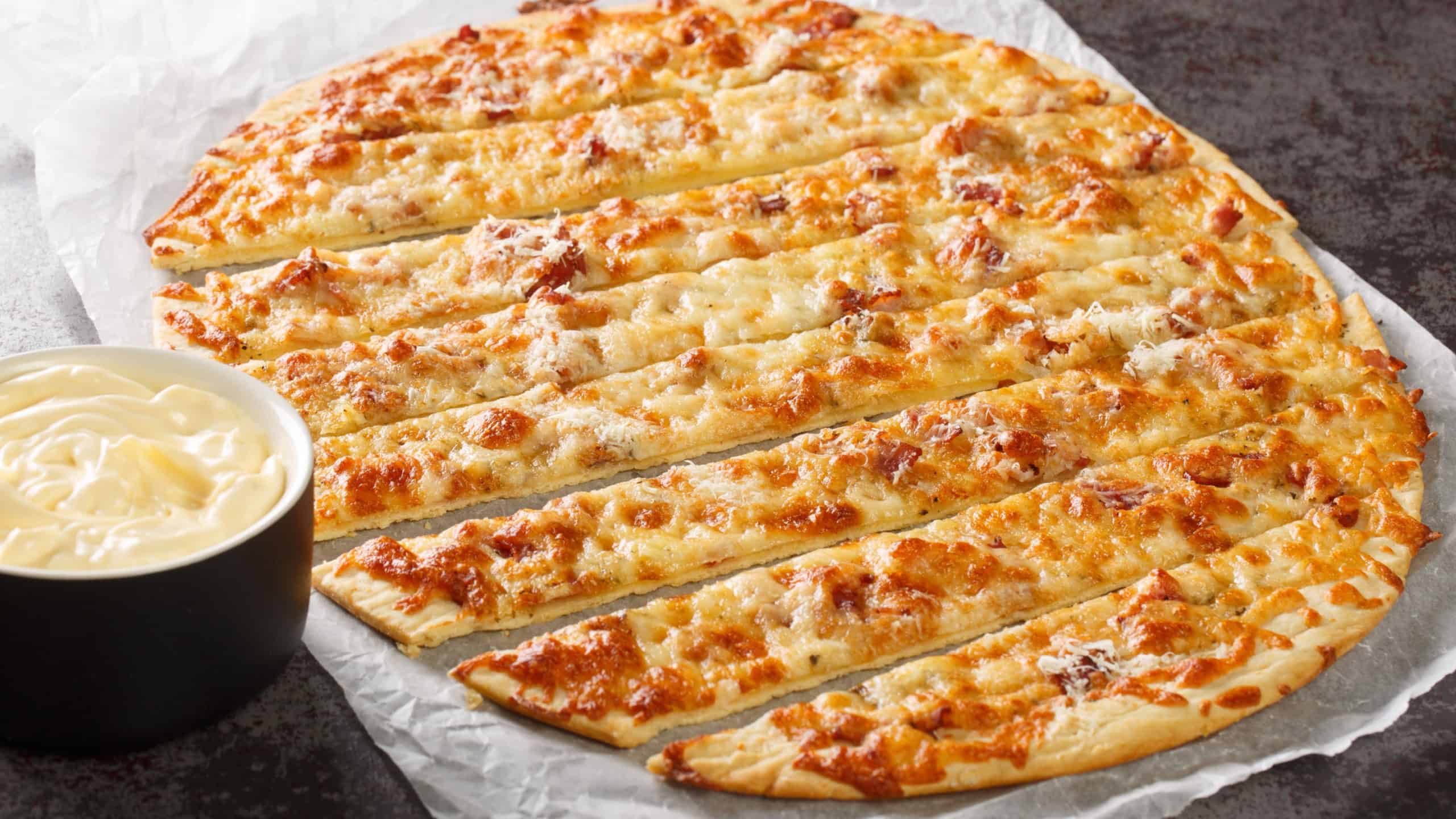 Canadian pizza Garlic Fingers and Donair Sauce close-up on paper on the table. horizontal