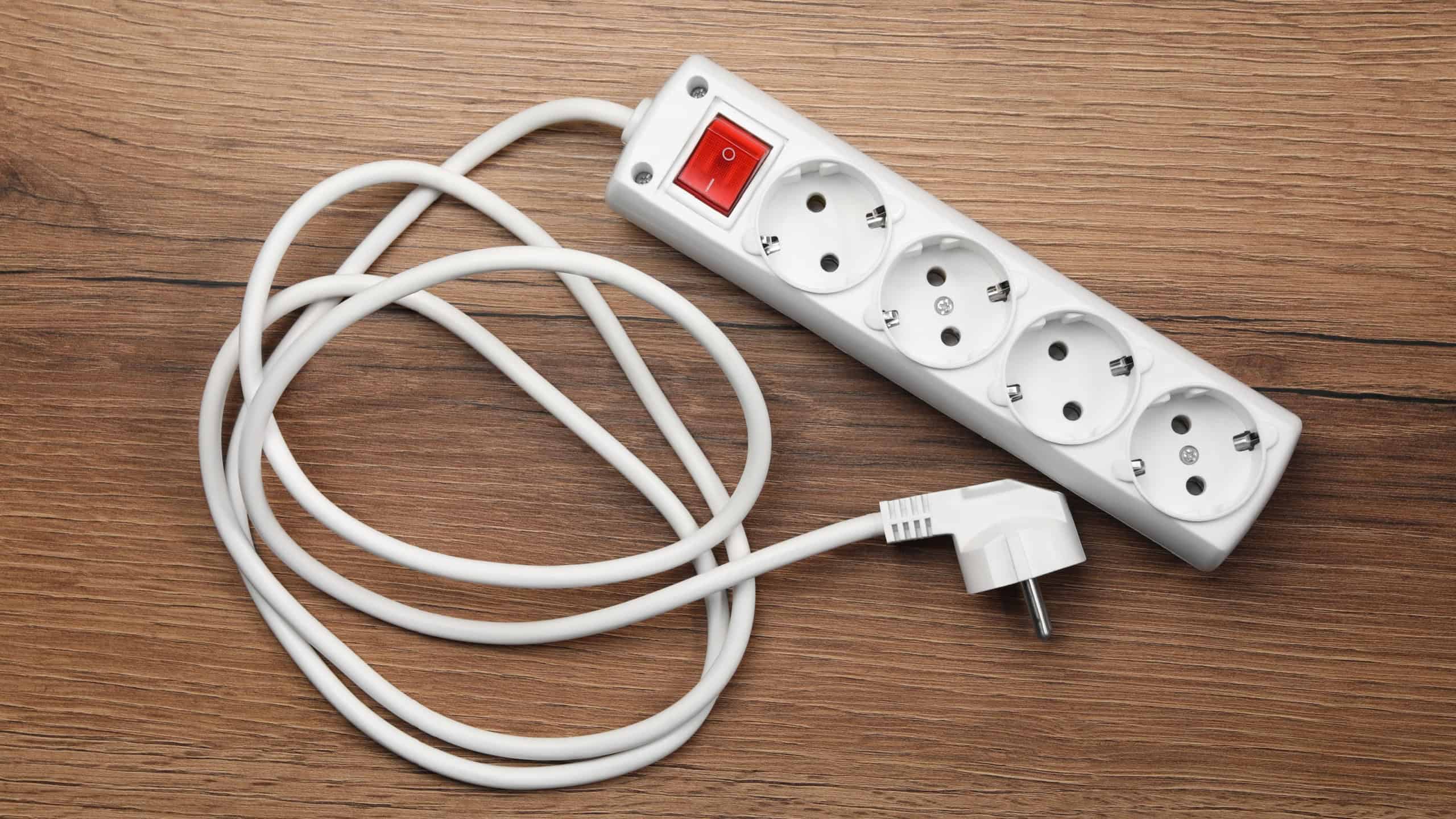 Power strip with extension cord on wooden floor, top view. Electrician's equipment
