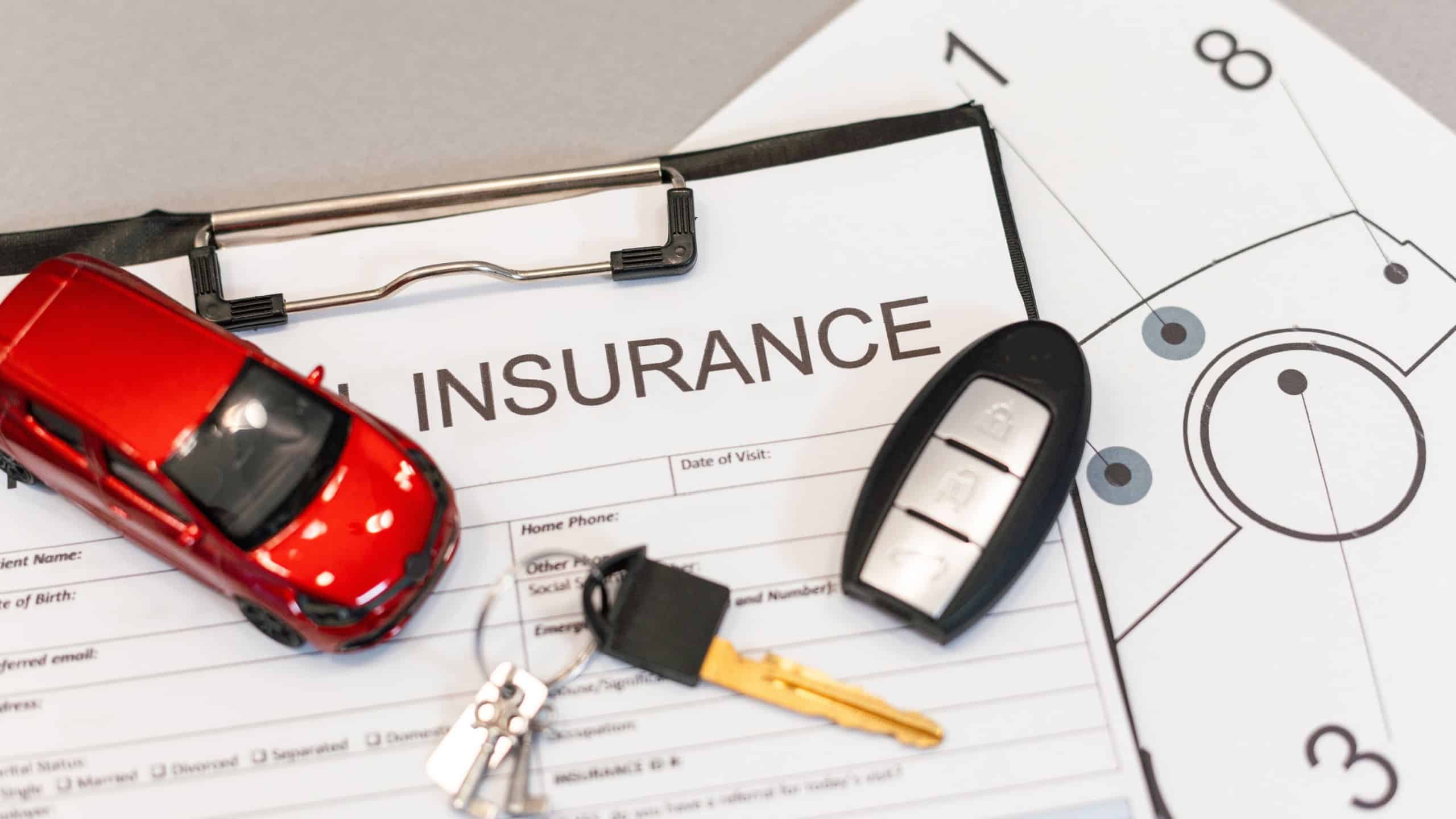Top view of car insurance claim form with car key and car toy on desk