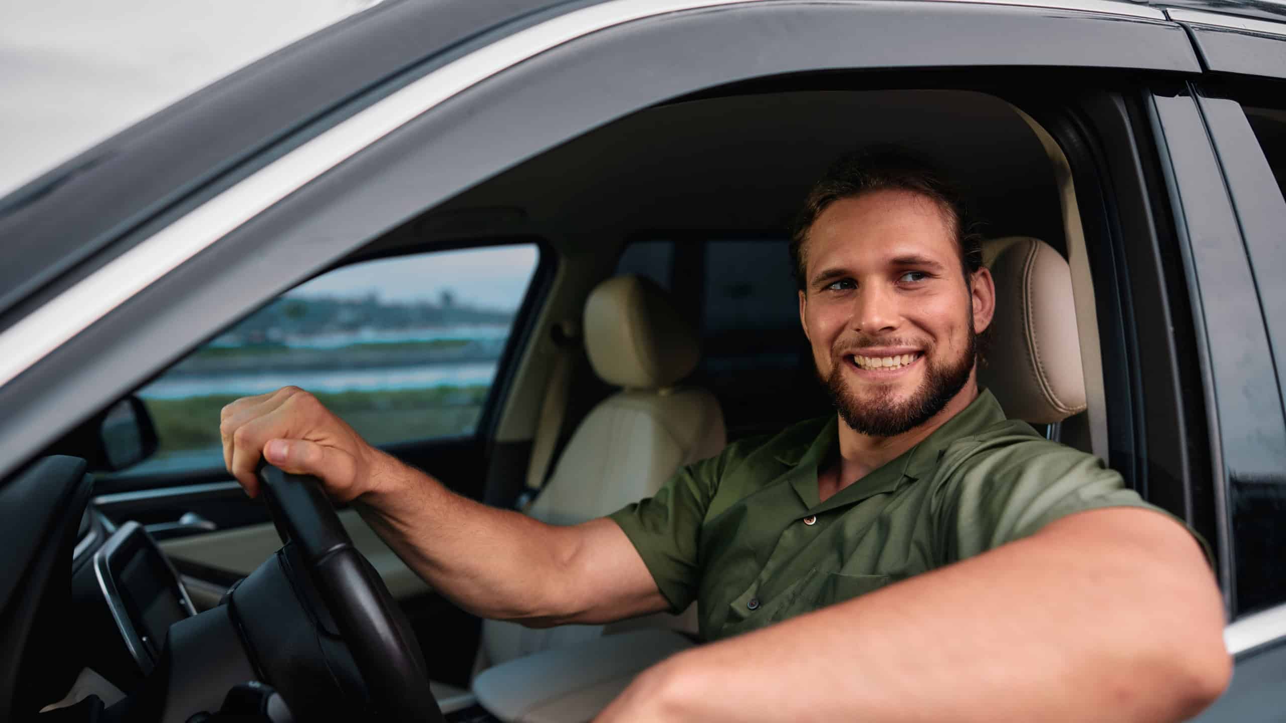 Smiling man driving a car with natural background and palm trees