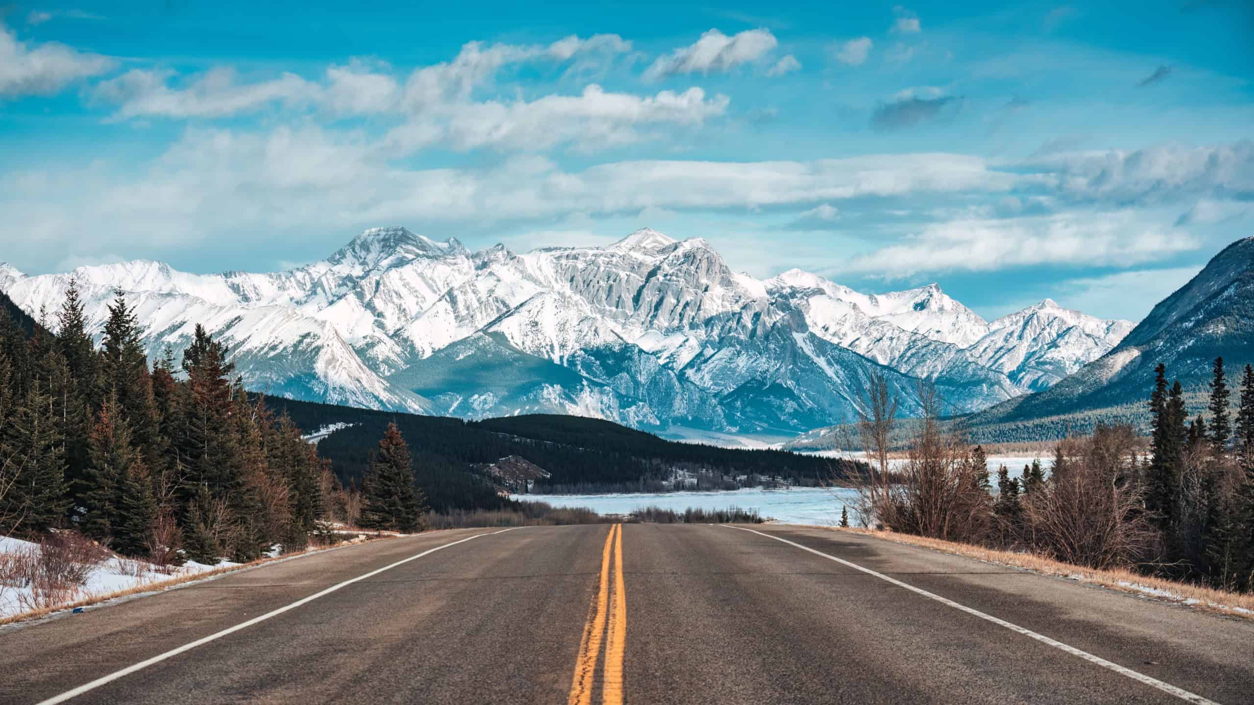 Road trip with car driving on highway road with snow covered rocky mountains in winter at Kootenay plains area, Alberta, Canada