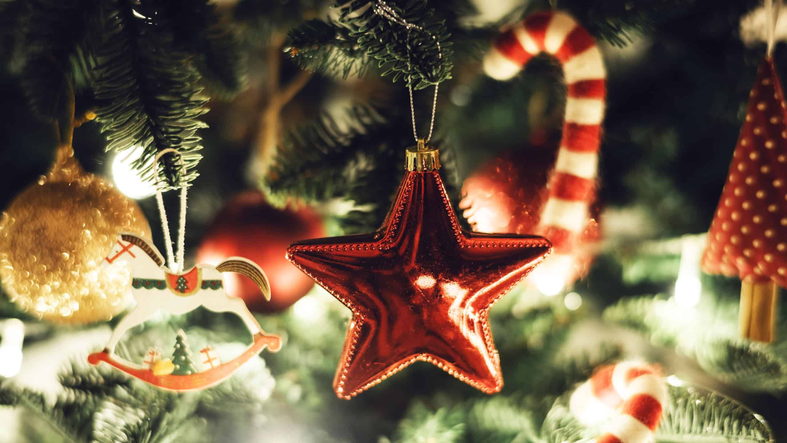 Close up of festive Christmas tree decoration with red star ornament, candy canes, and golden decorations. Christmas tree lights, red star, and candy canes create a holiday atmosphere.