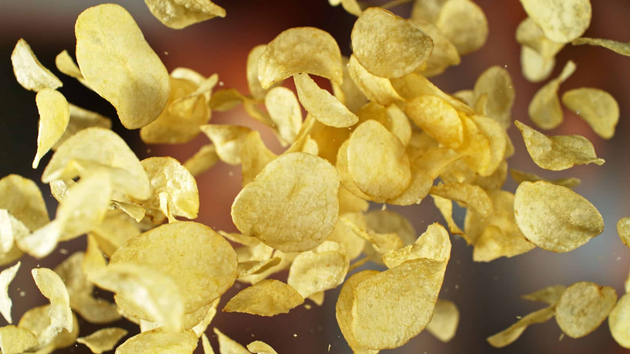 Flying Potato Chips, Fried Potatoes Flying up in the Air. Concept of Junk Food.