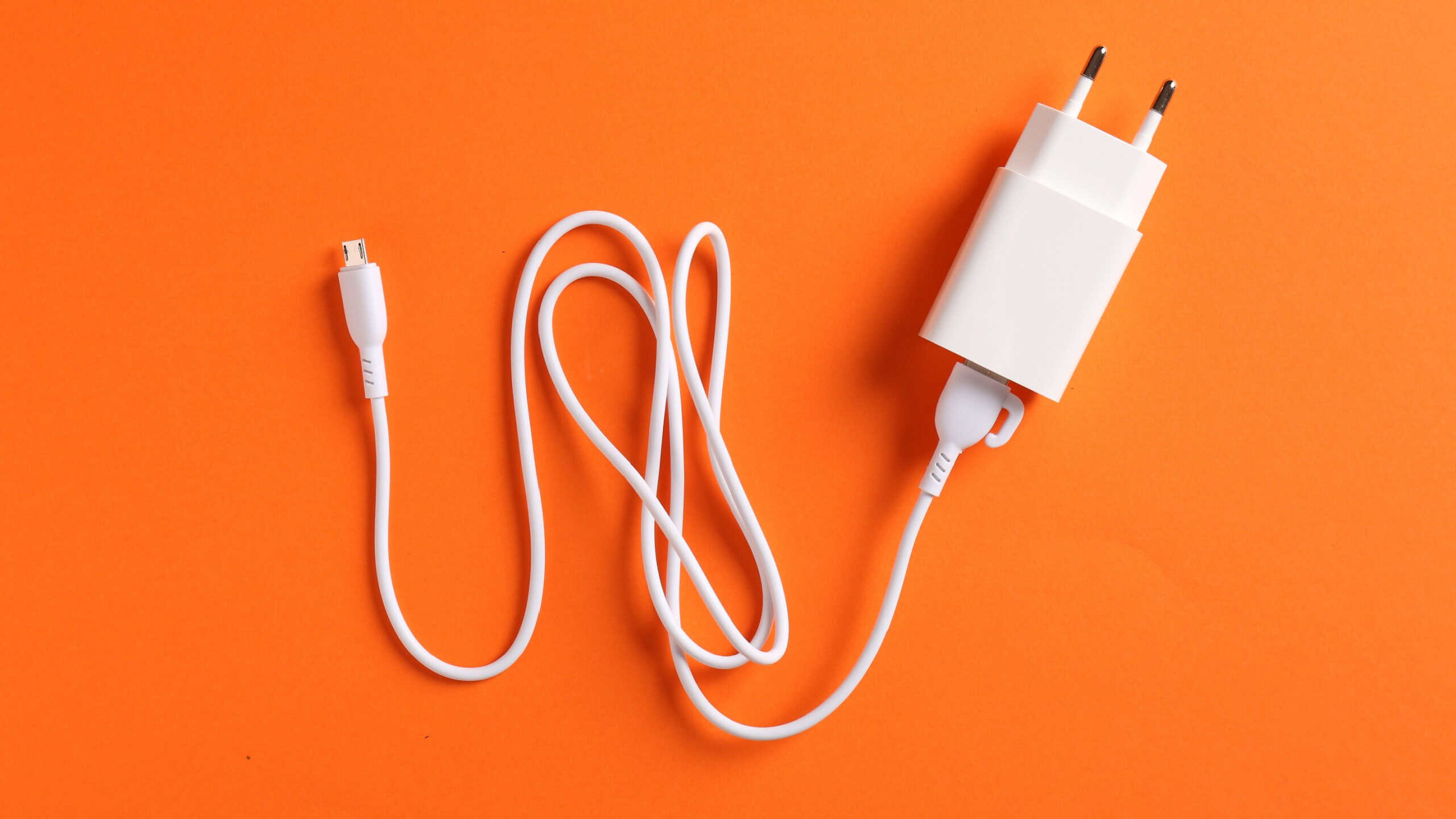 USB power adapter with charge cable on orange background, top view