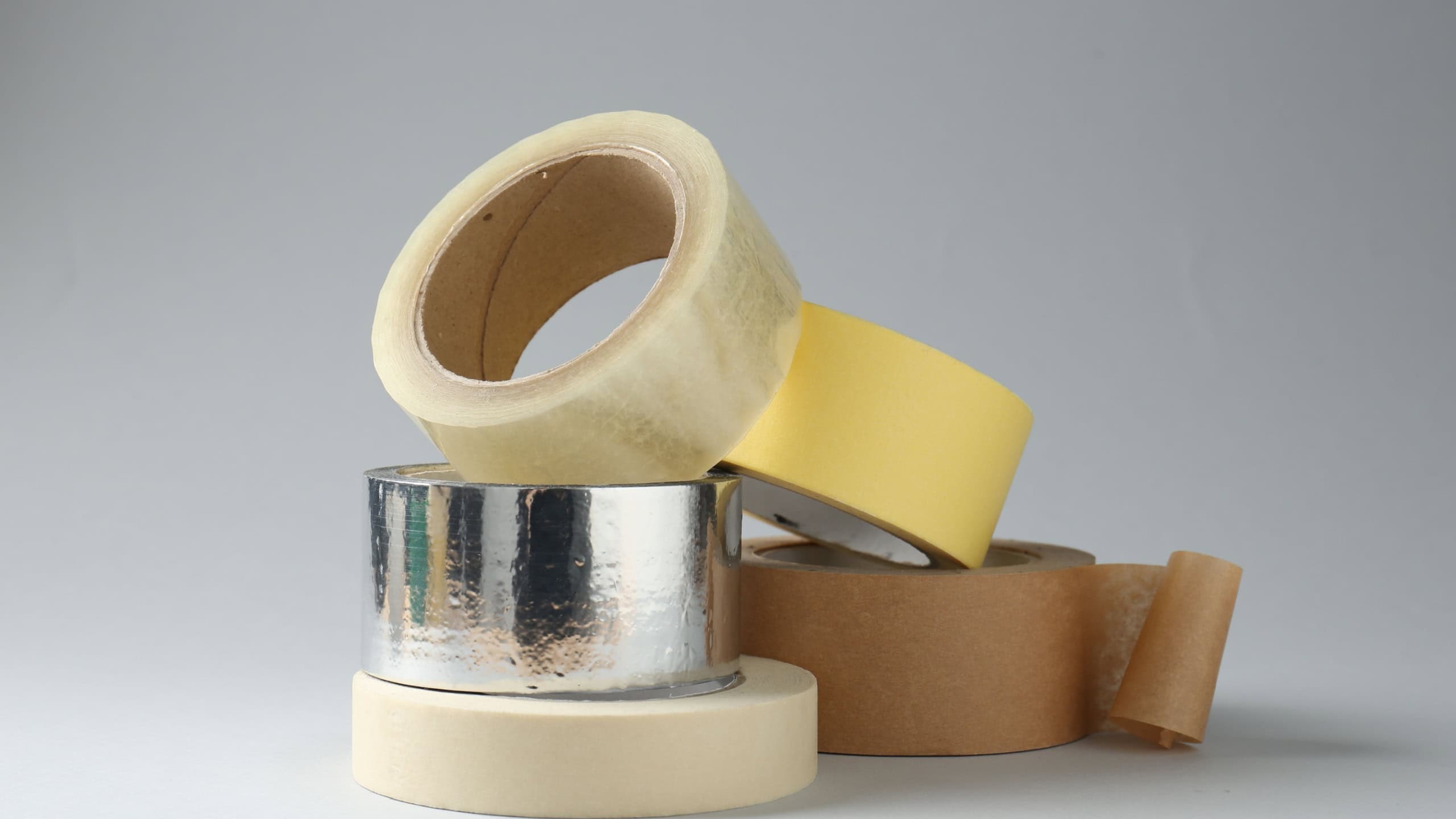 Rolls of different adhesive tapes on grey background