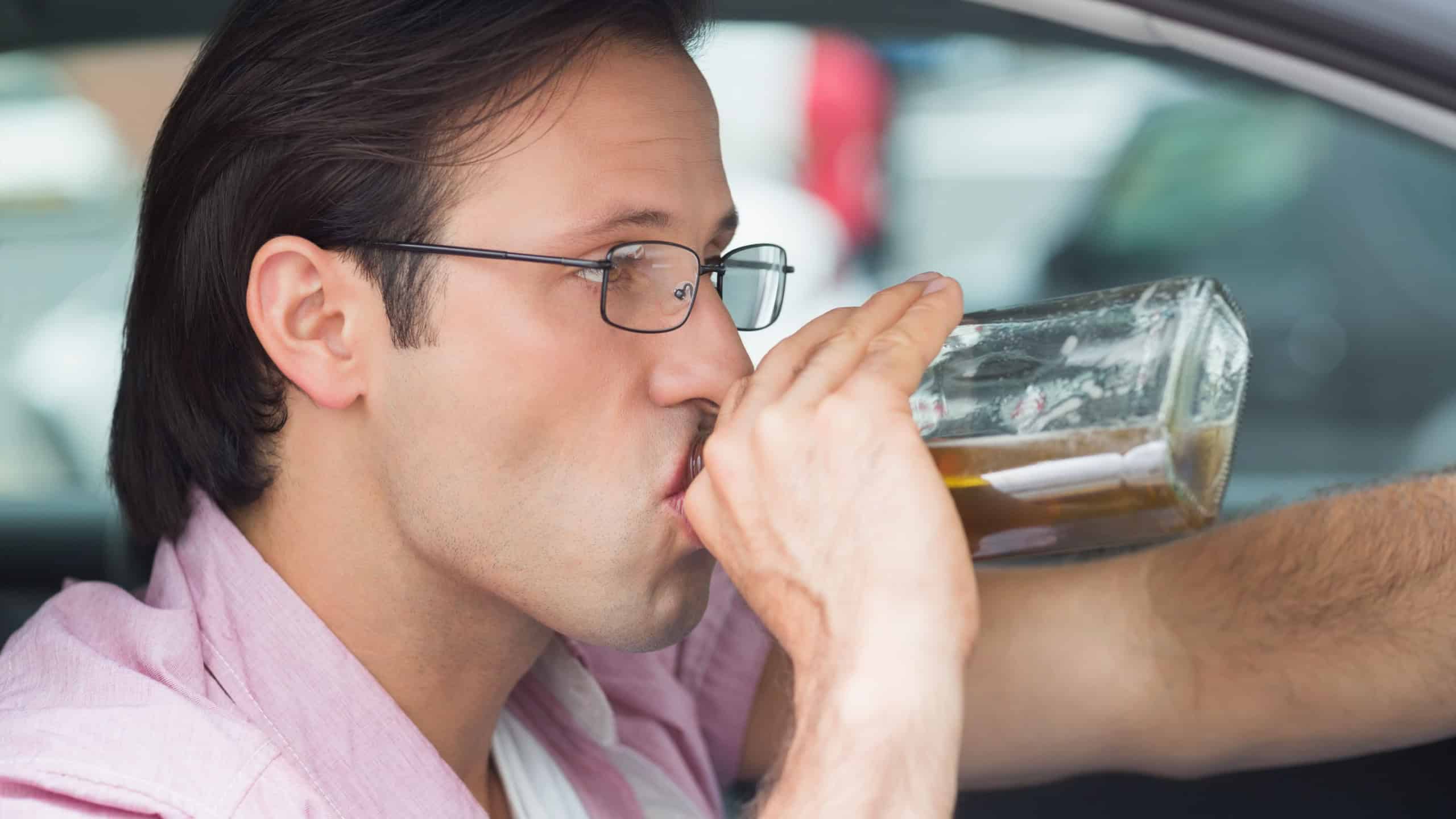 Man drinking alcohol while driving in his car