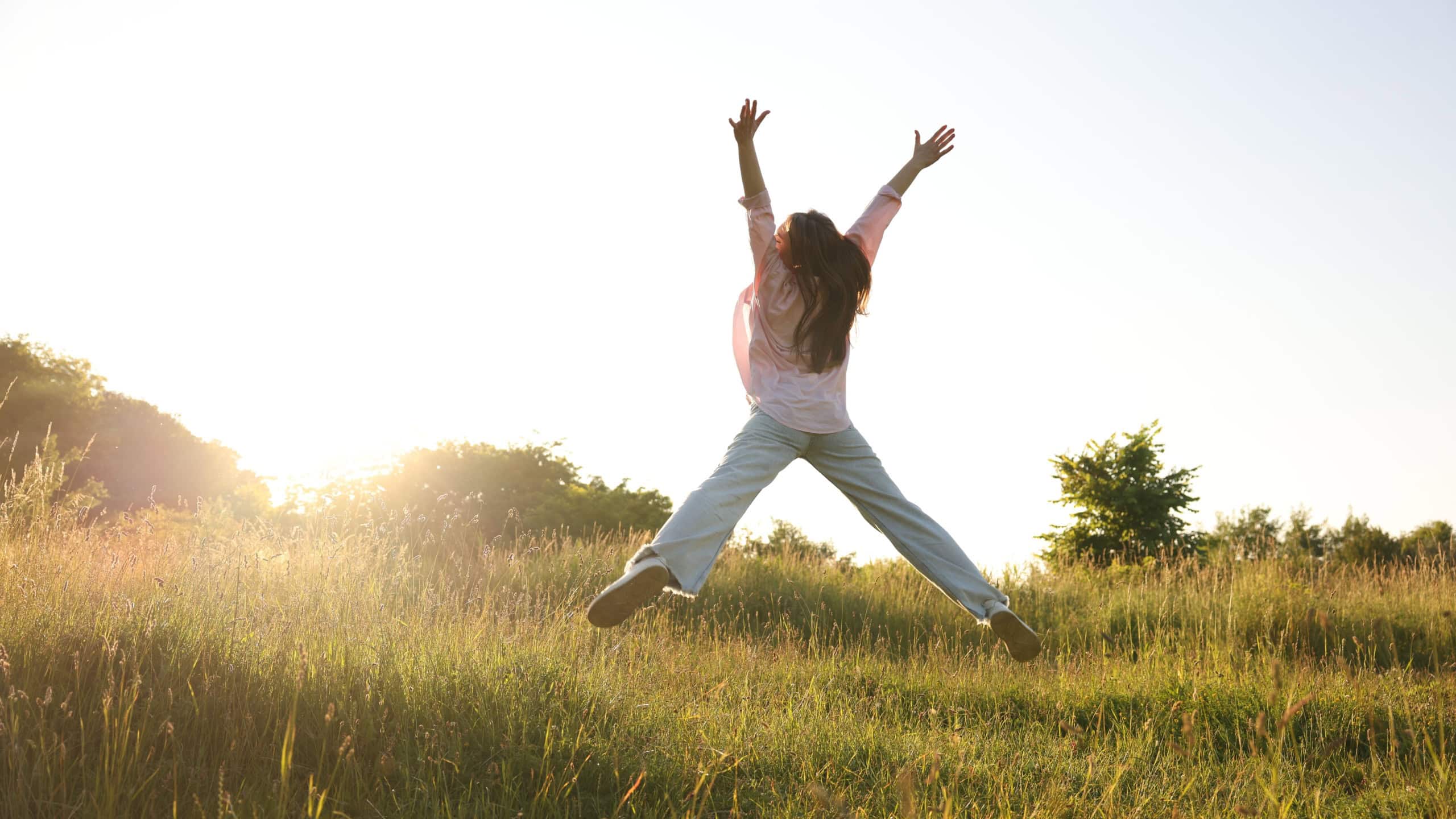 Feeling freedom. Woman jumping in nature, back view