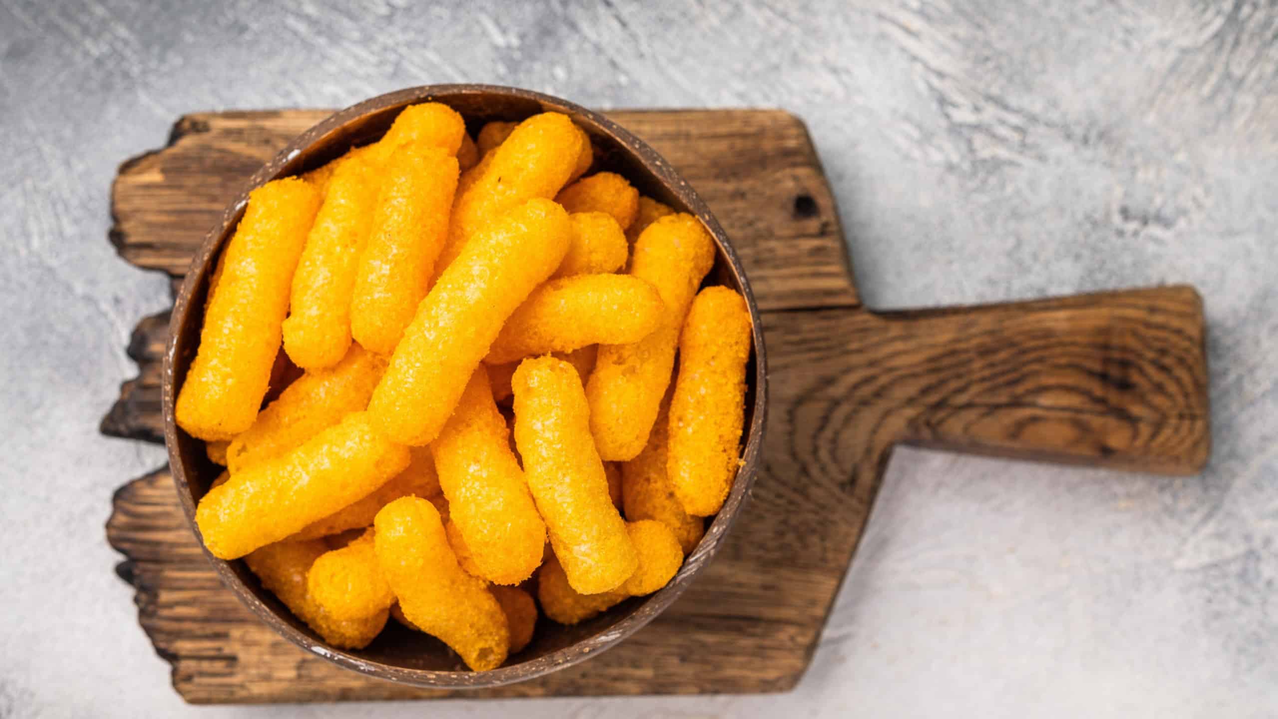 Irresistible Cheese puffs, cheese snacks bursting with bold flavors and a satisfying crunch. grey background. top view.
