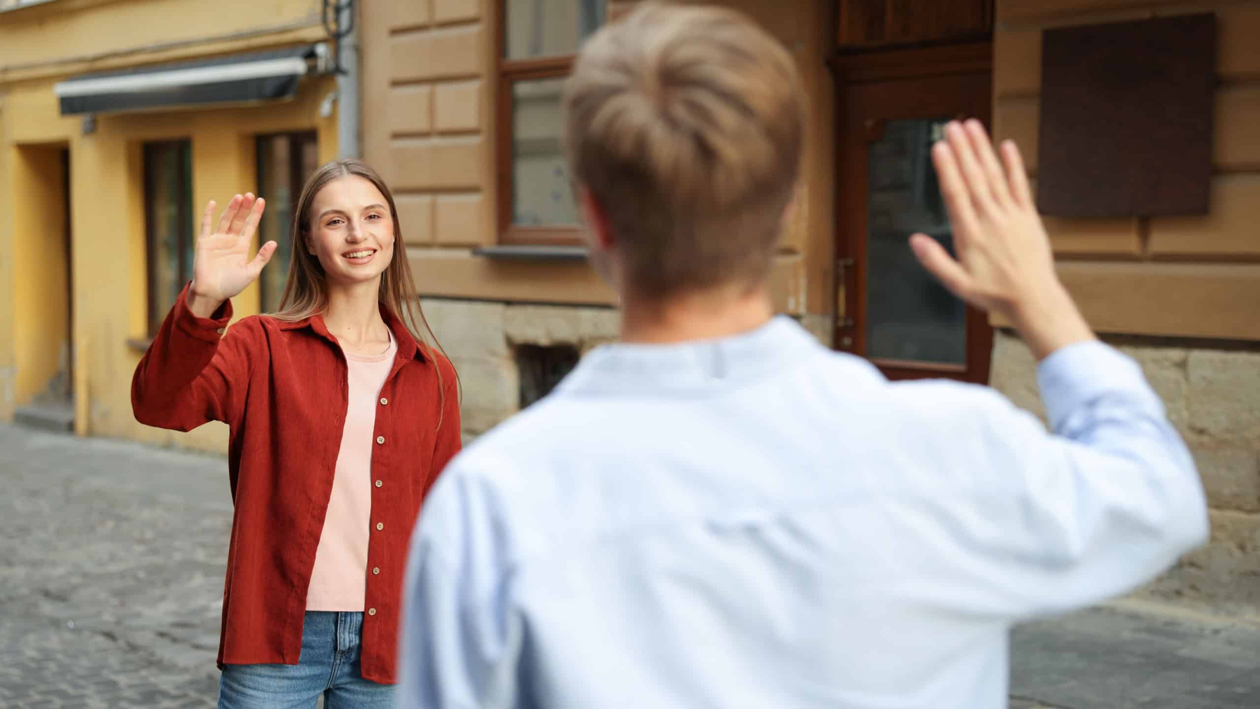 Goodbye. Man waving to his girlfriend on city street, selective focus