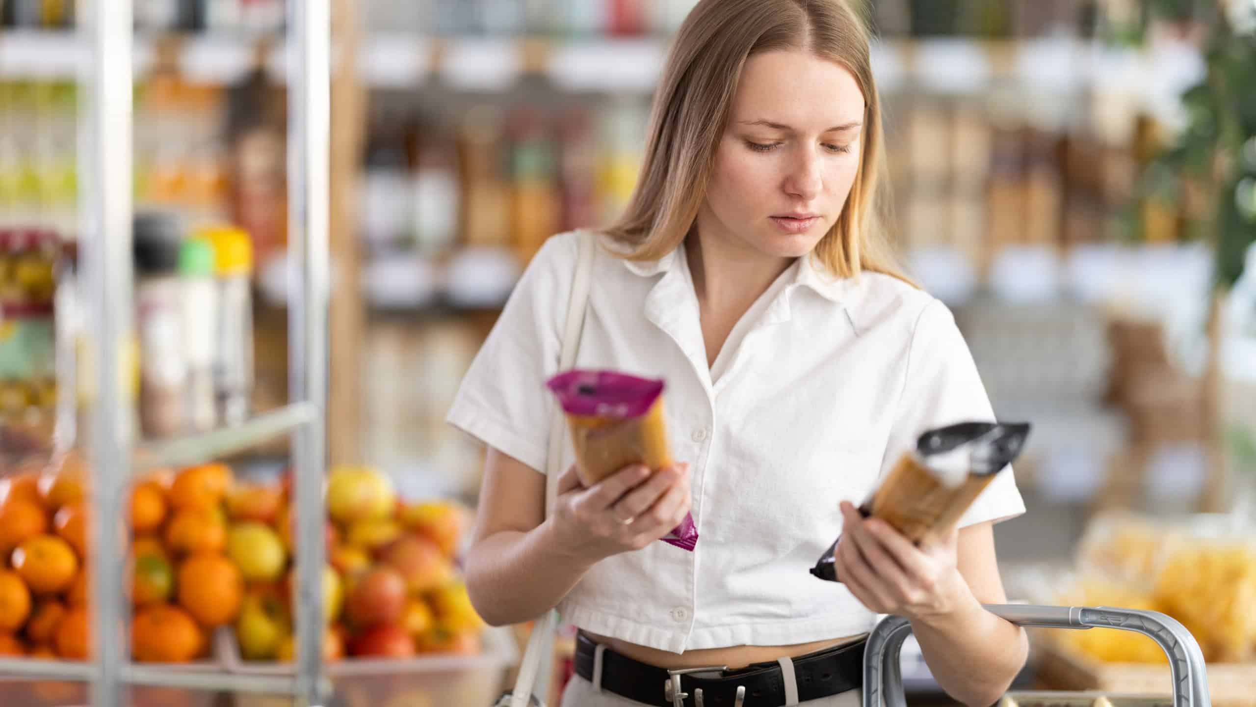 Young woman buyer chooses spaghetti in package in grocery store..