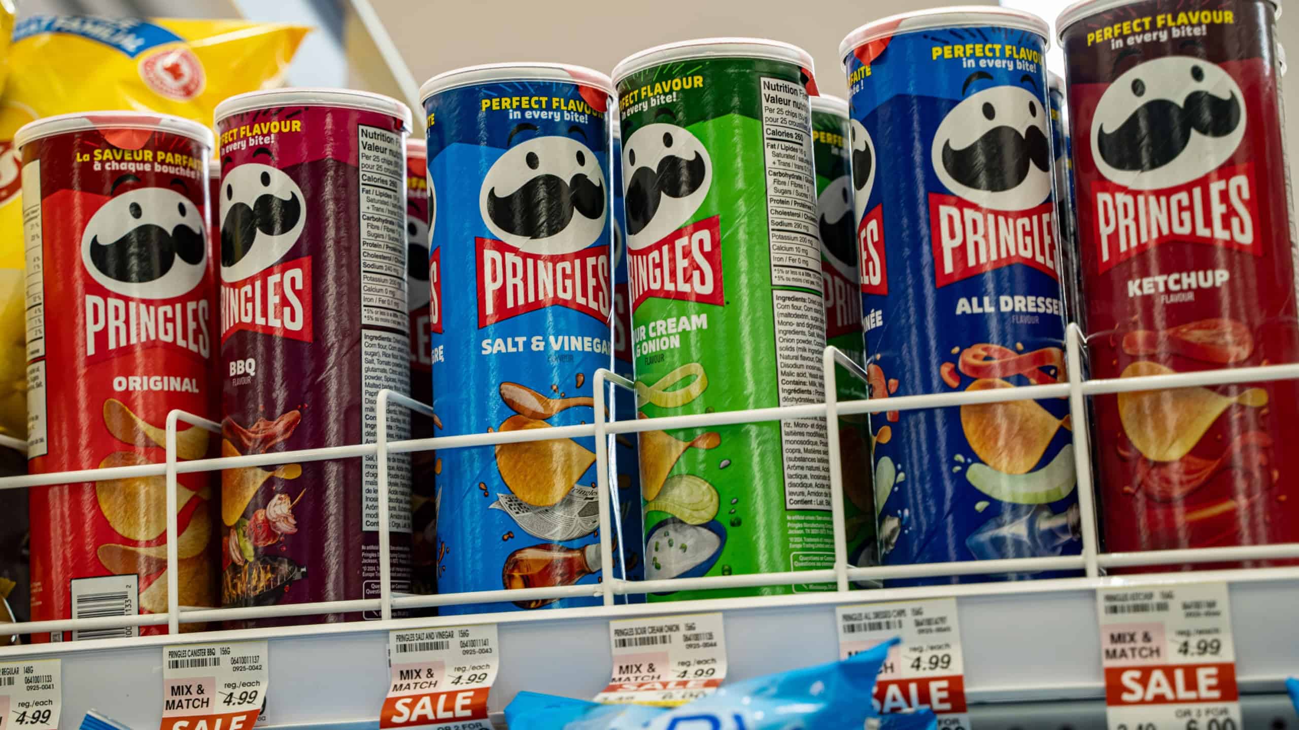 Assorted Pringles chips cans in various flavors on store shelf. Toronto, Canada - September 18, 2025.