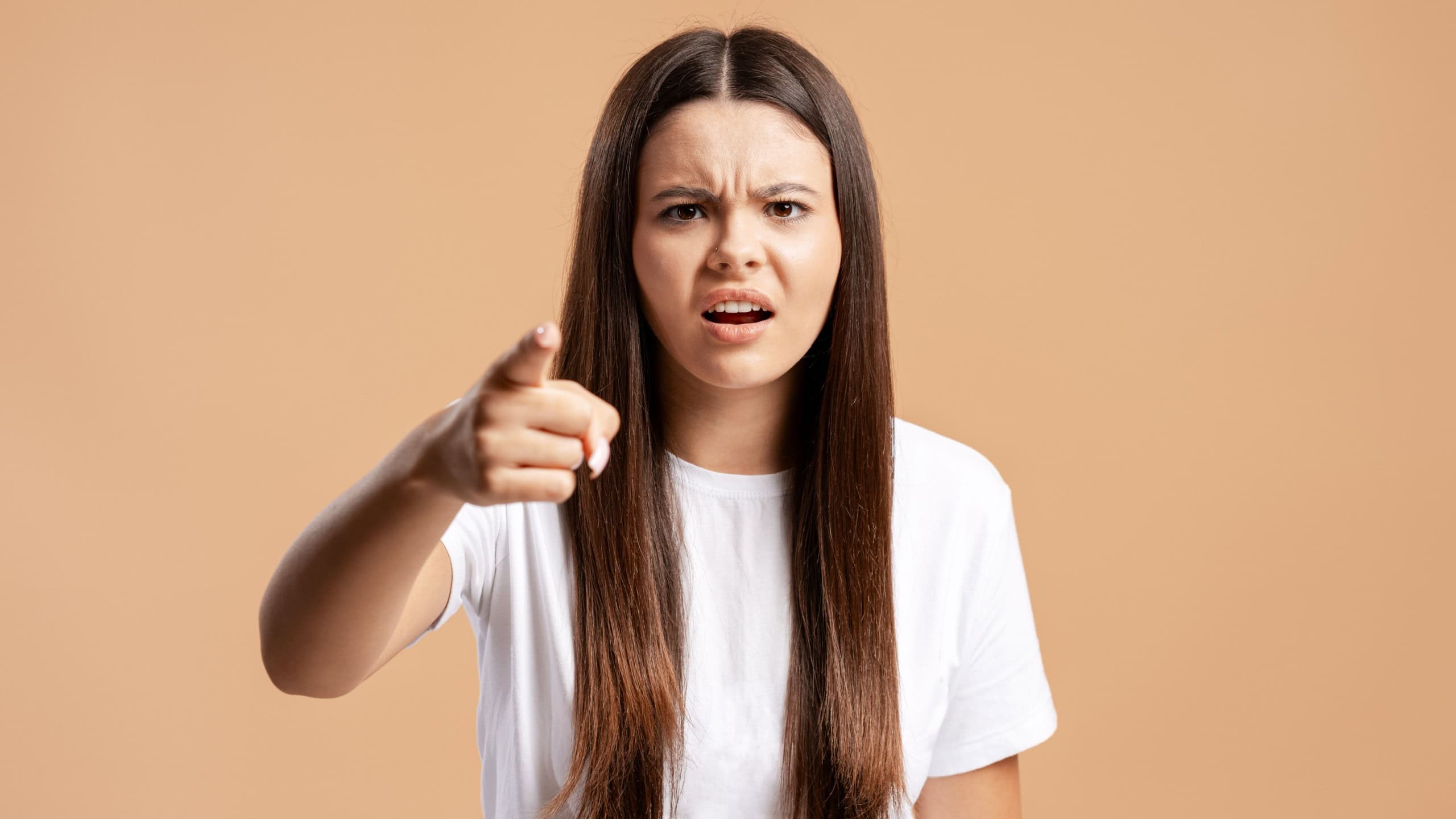 Young woman pointing forward with an angry expression, showing frustration, accusation, and blame
