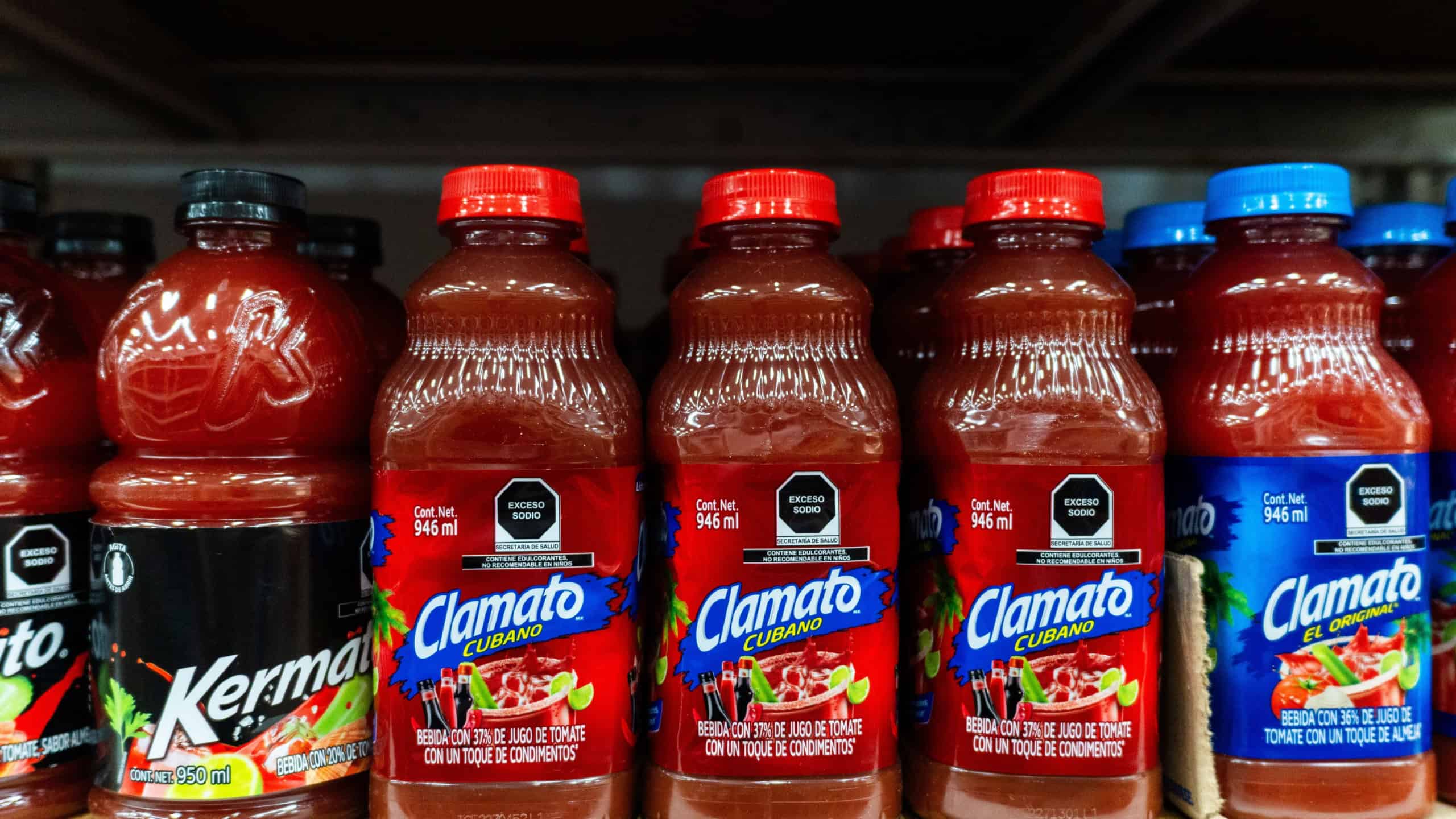 Display stand with bottles of Clamato tomato juice in different flavors.