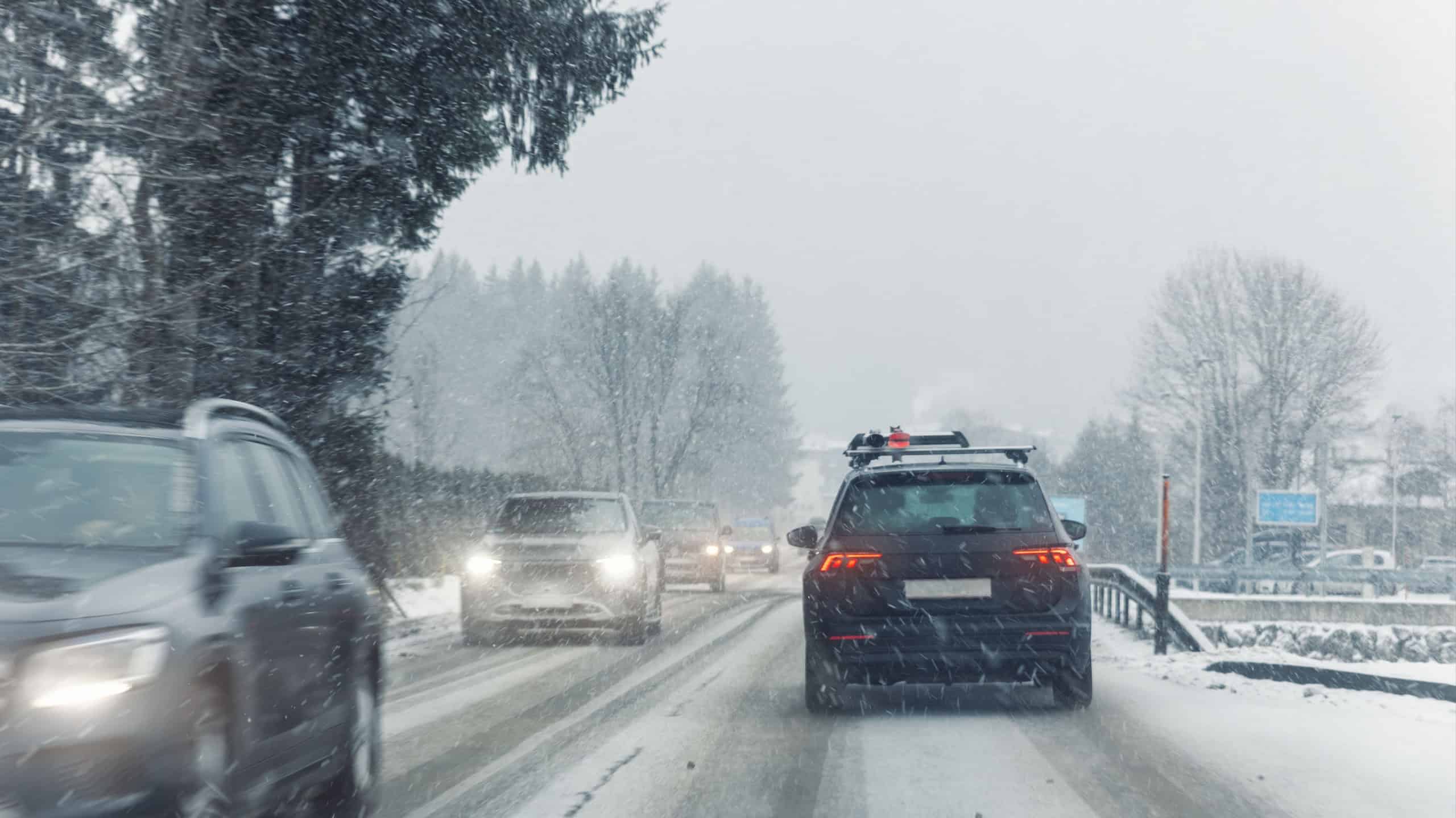 Scenic view snow covered city highway slippery mountain alpine road drive cars moving fast speed motion. Snowfall danger blizzard bad winter weather conditions. Cold snowy day snowstorm background.