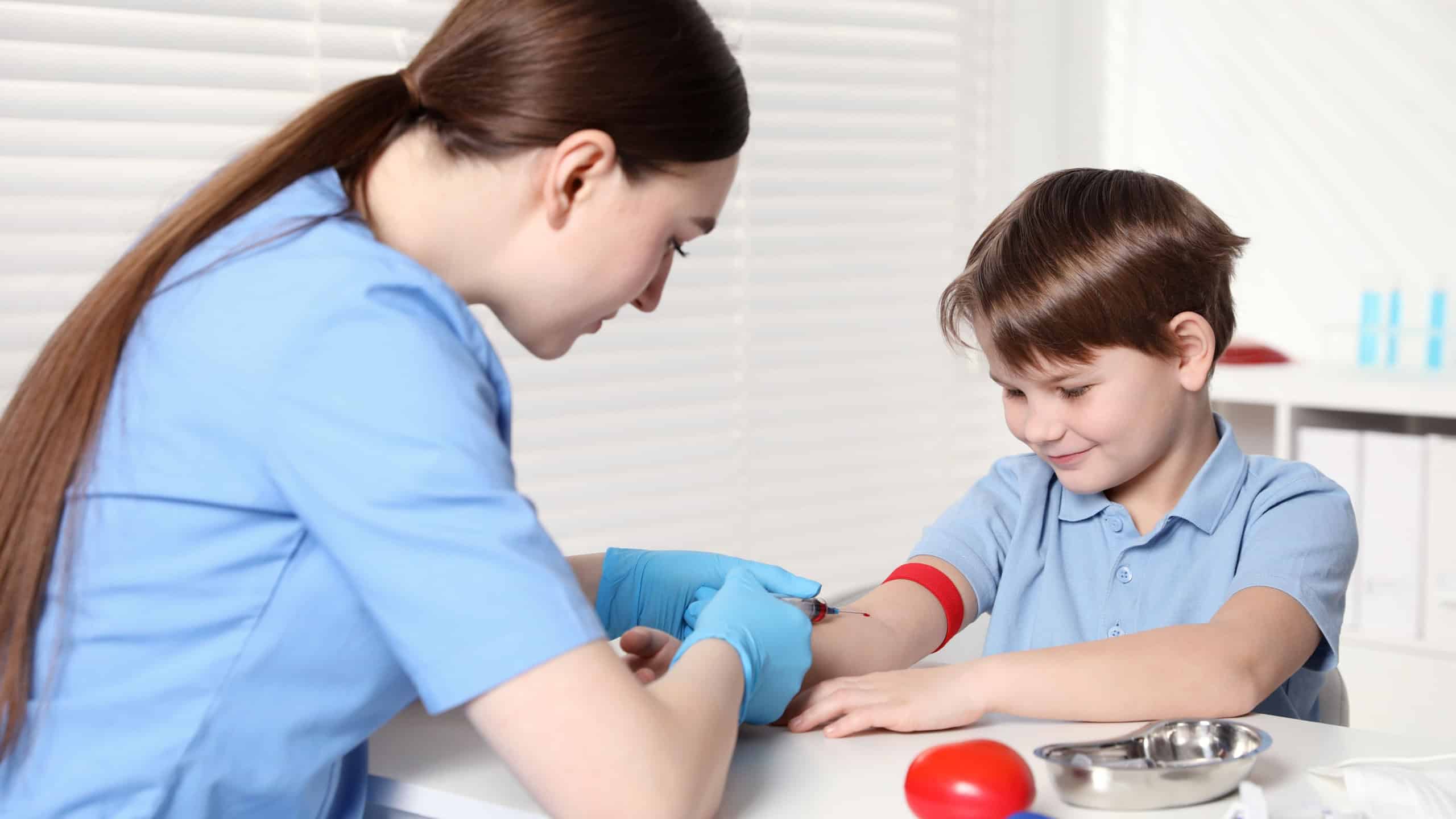 Nurse drawing little boy's blood sample in clinic