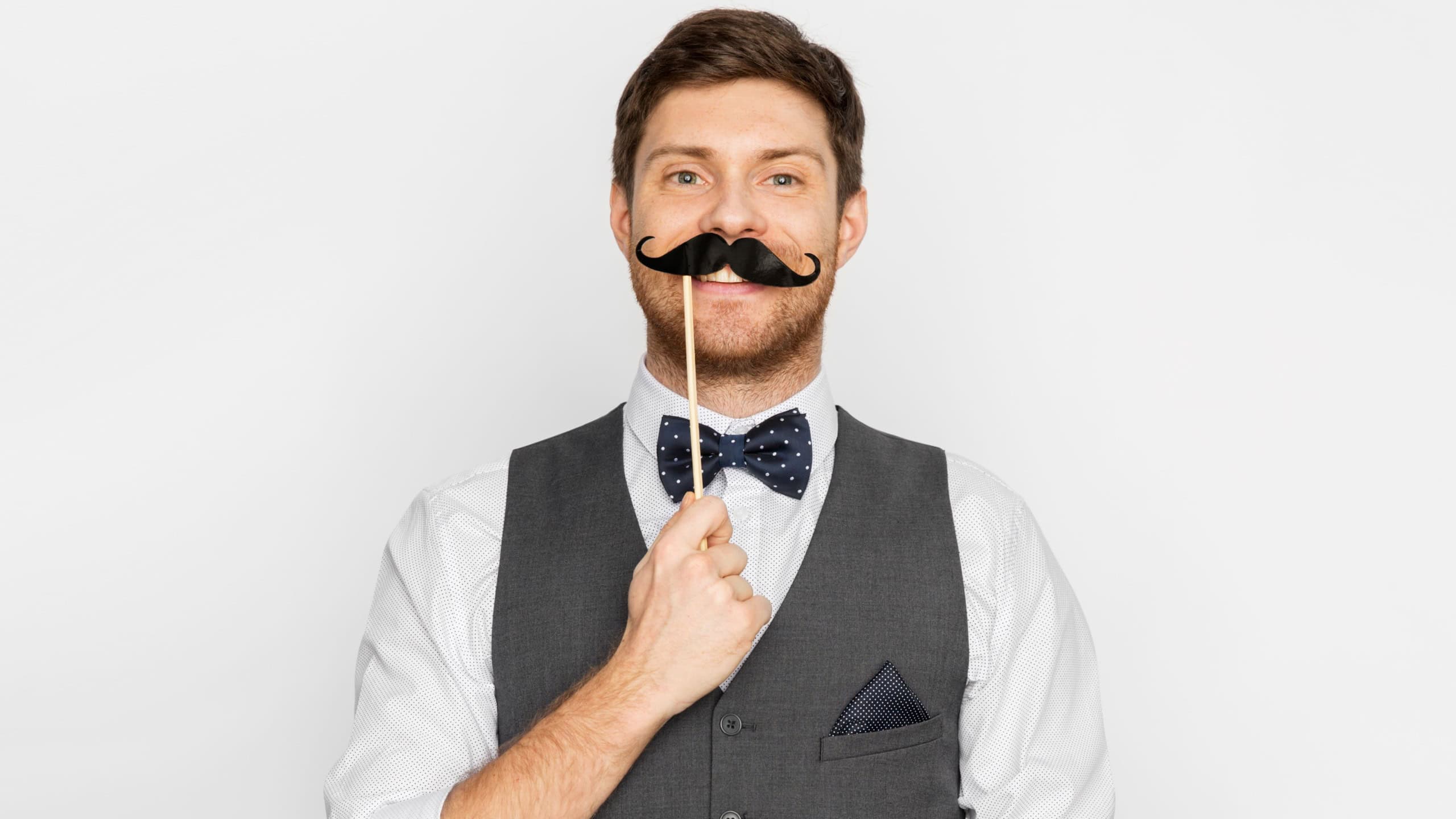 people, party and charity concept - happy young man with fake black moustache party prop