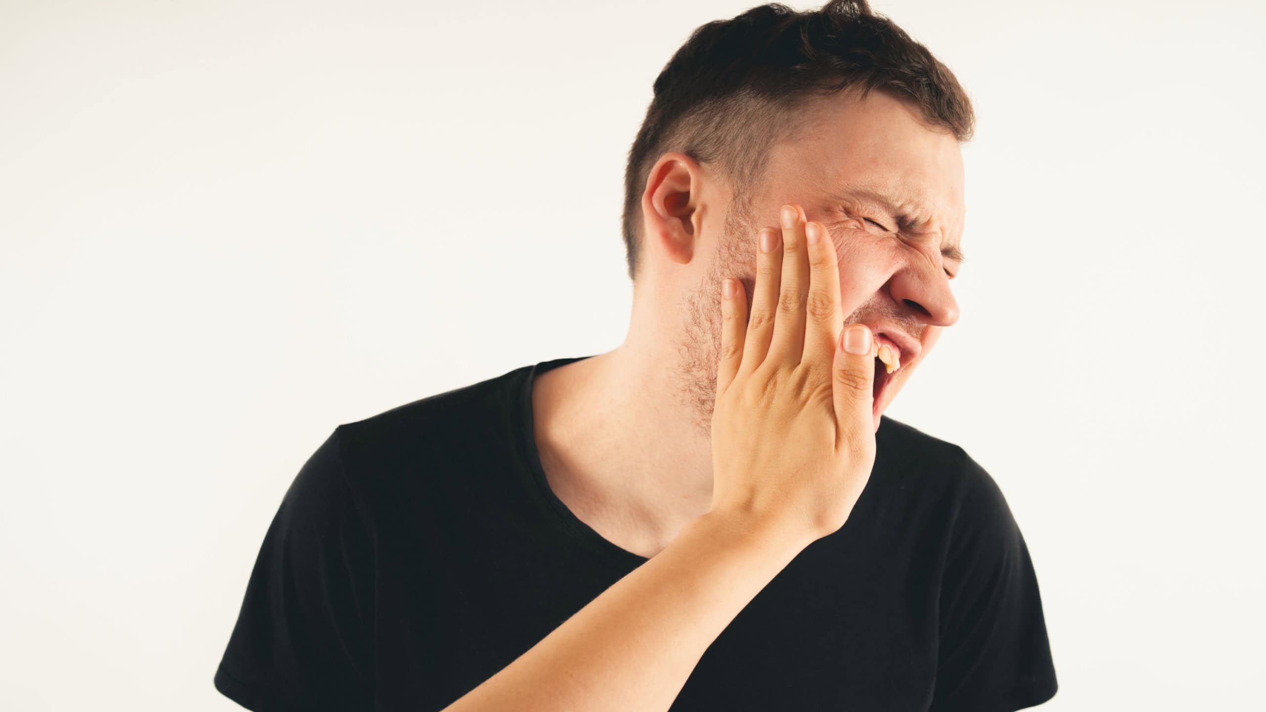 Crop person slapping scared man in face. Emotional male getting slapped in face while shouting with closed eyes in fear on white background