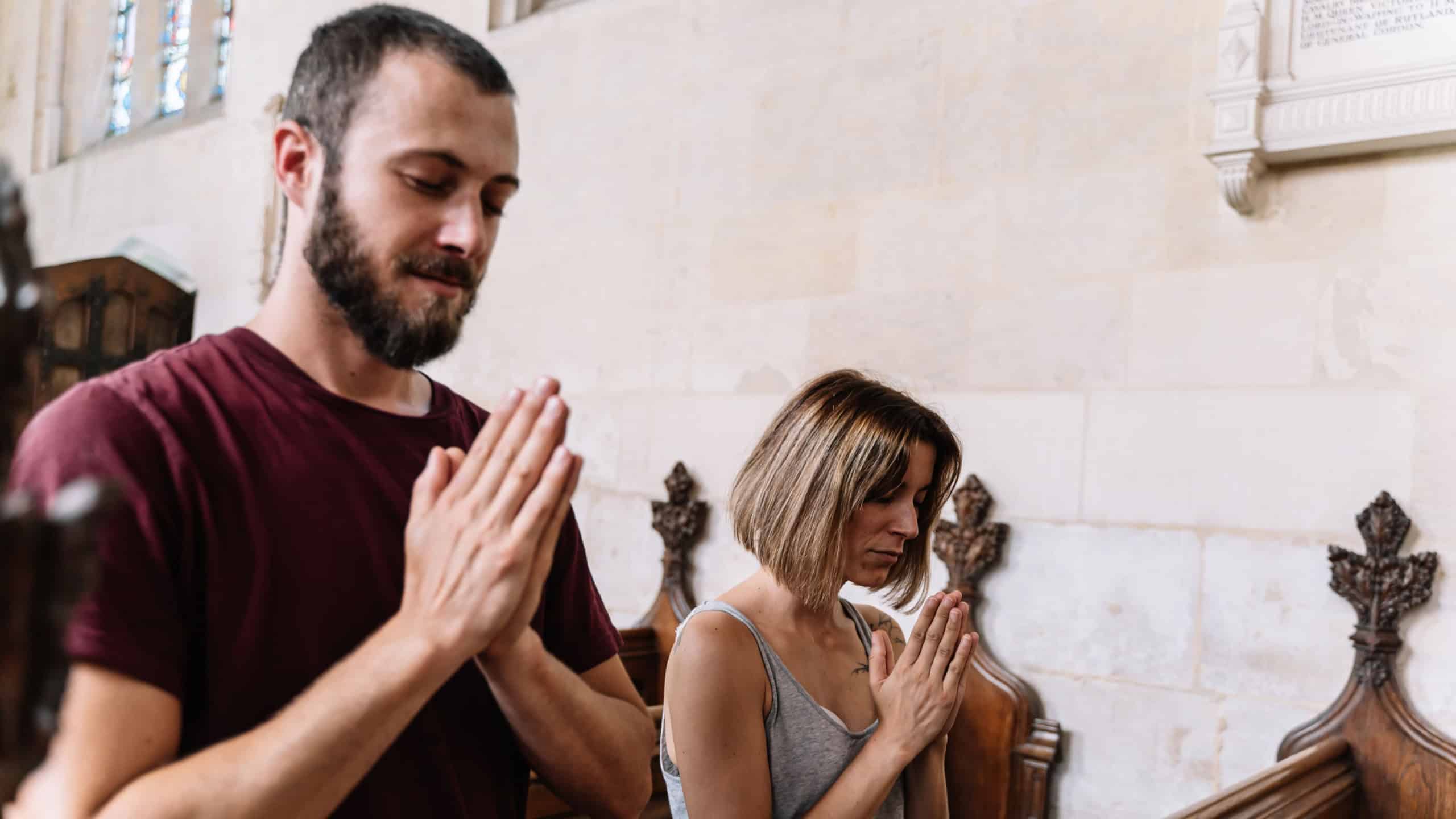 Young couple praying in a church. Travel concept