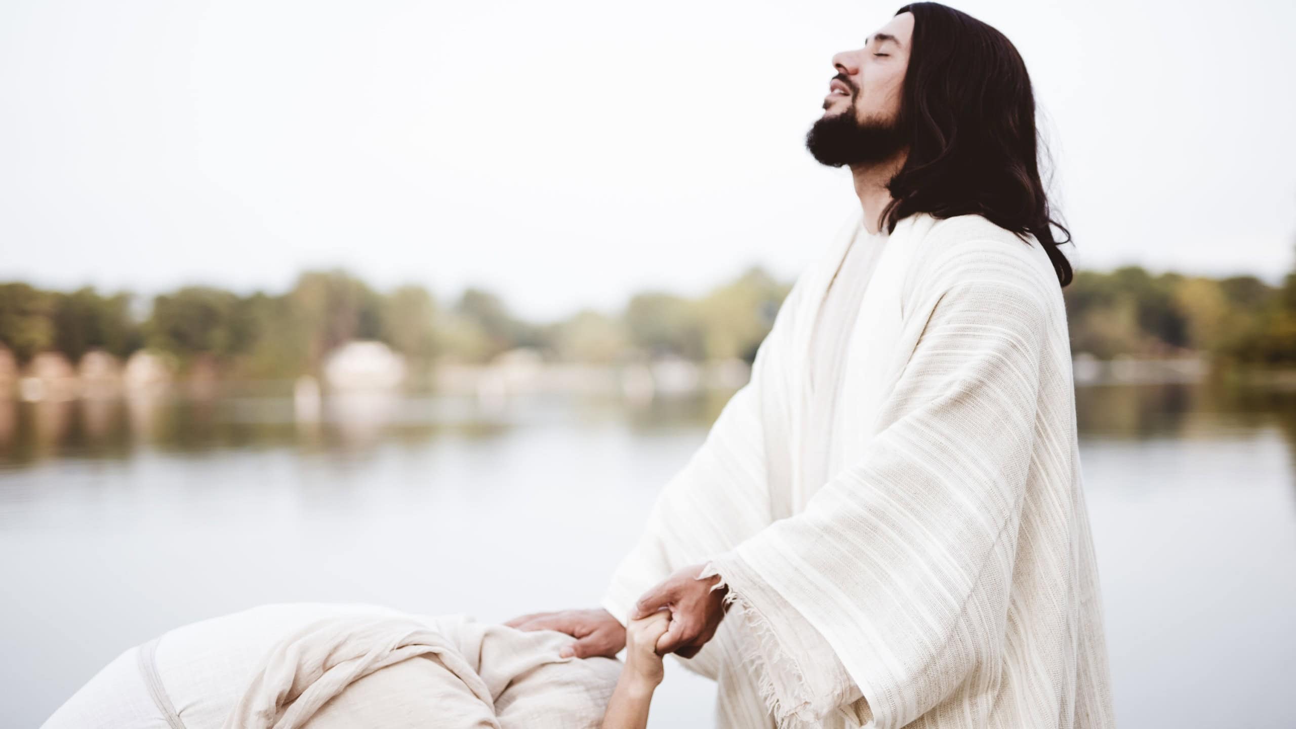 A shallow focus shot of Jesus Christ healing a female with his hand on her head