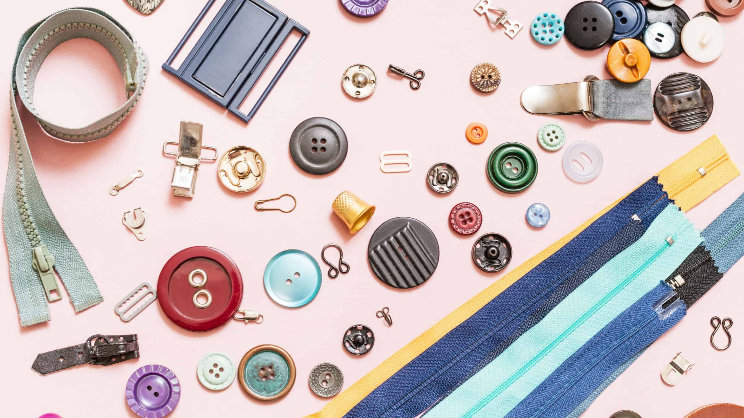 Top view of set of various sewing items on pink background