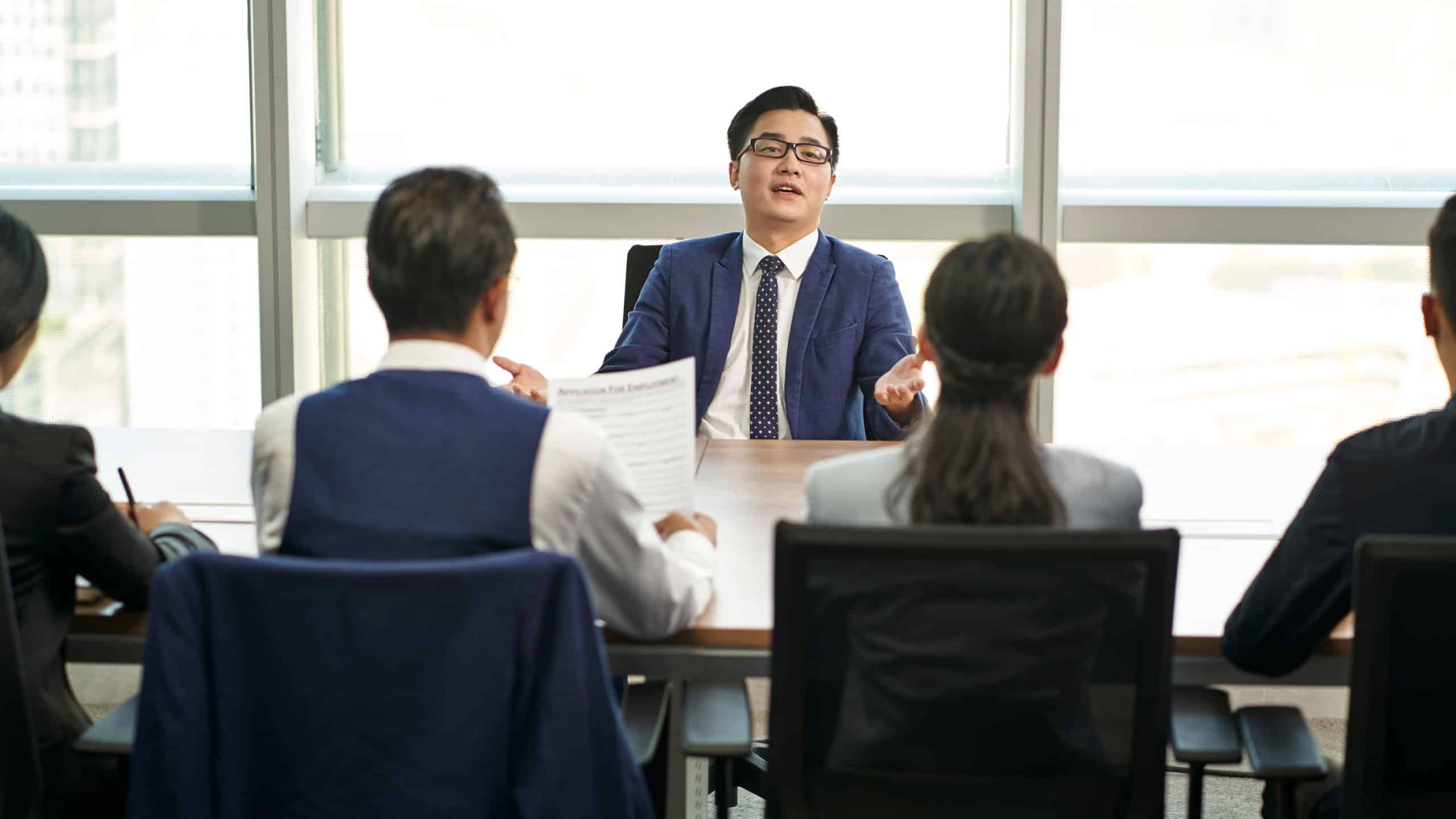 over confident young asian business person talking big in front of hr interviewers during job interview