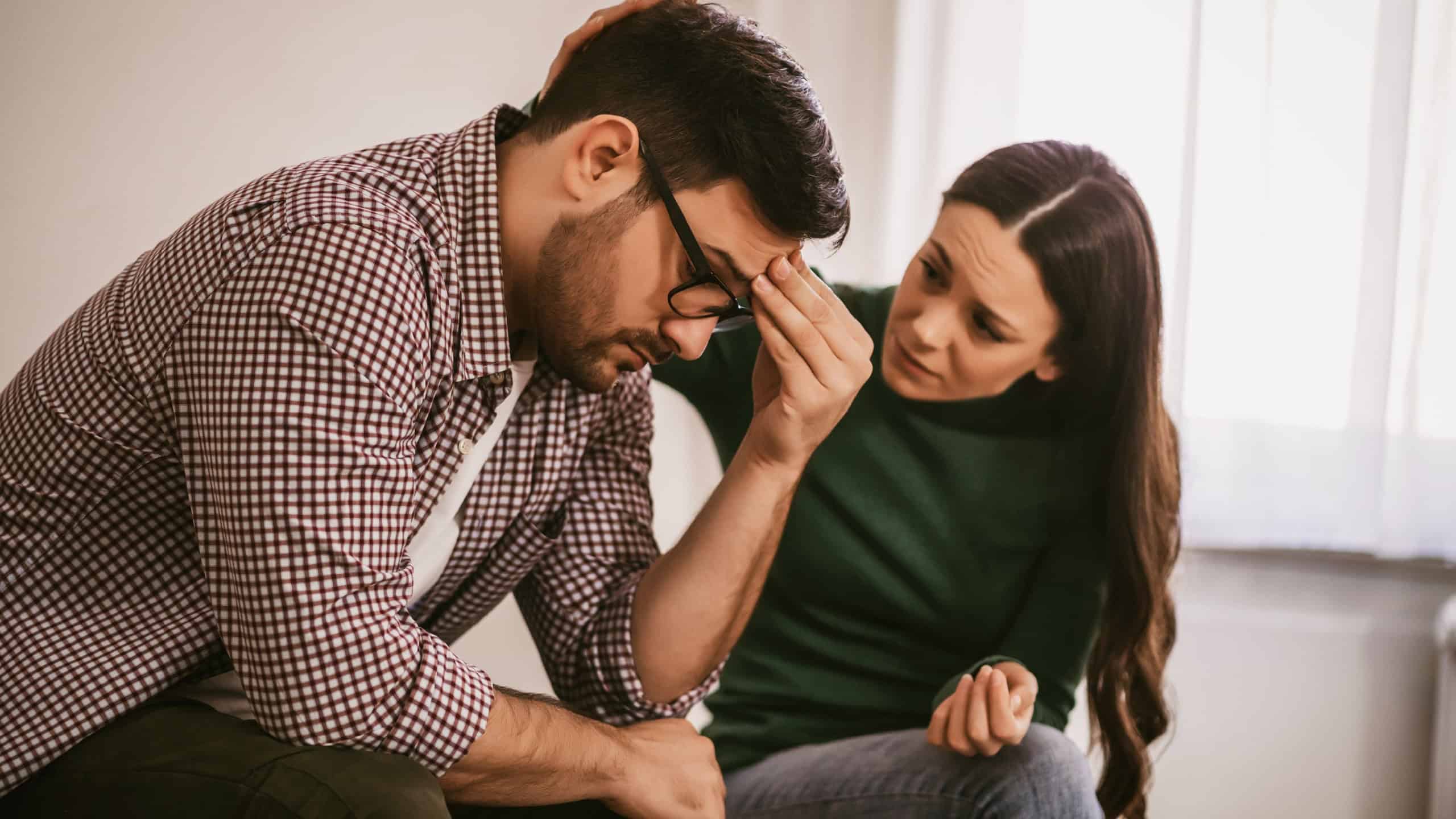 Man is sad and depressed, his wife is consoling him.