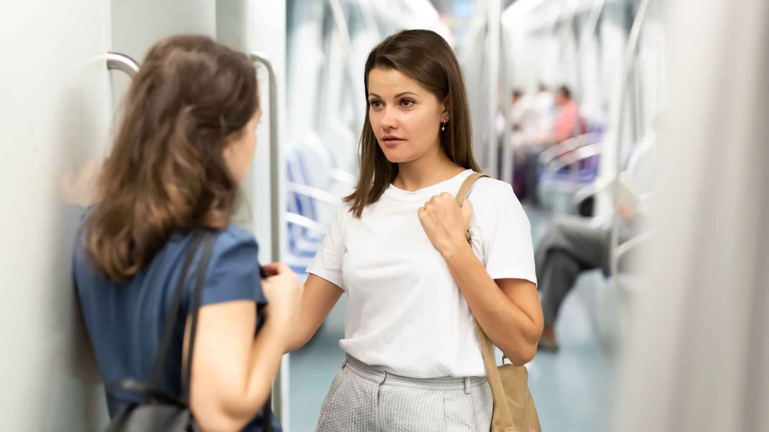 Two young women passengers talking in subway car on way to work..